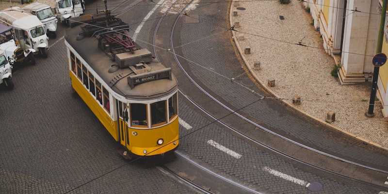 Žlutá tramvaj projíždějící městskými kolejemi