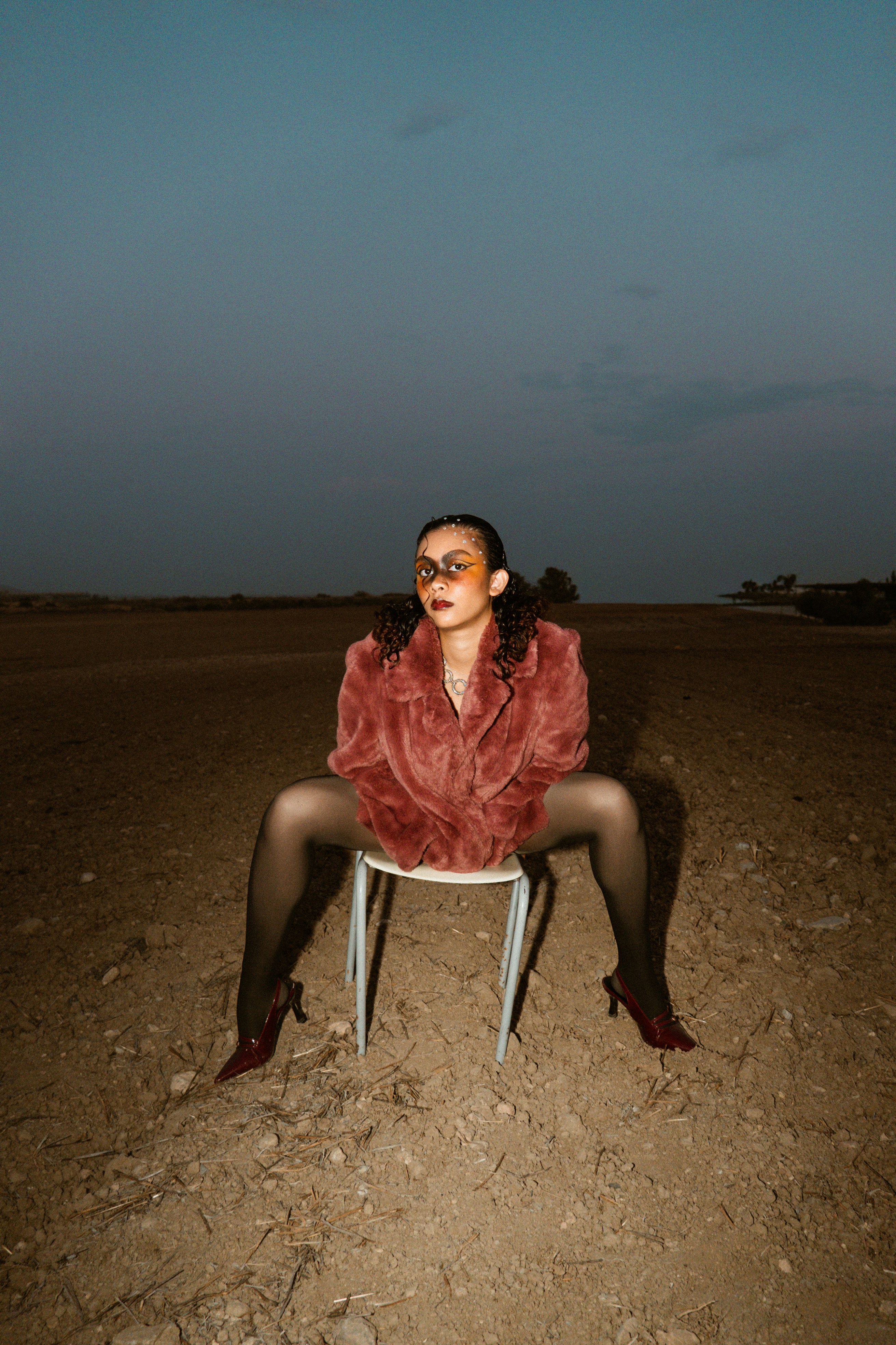 Femme en manteau de fourrure assise sur une chaise dans un champ