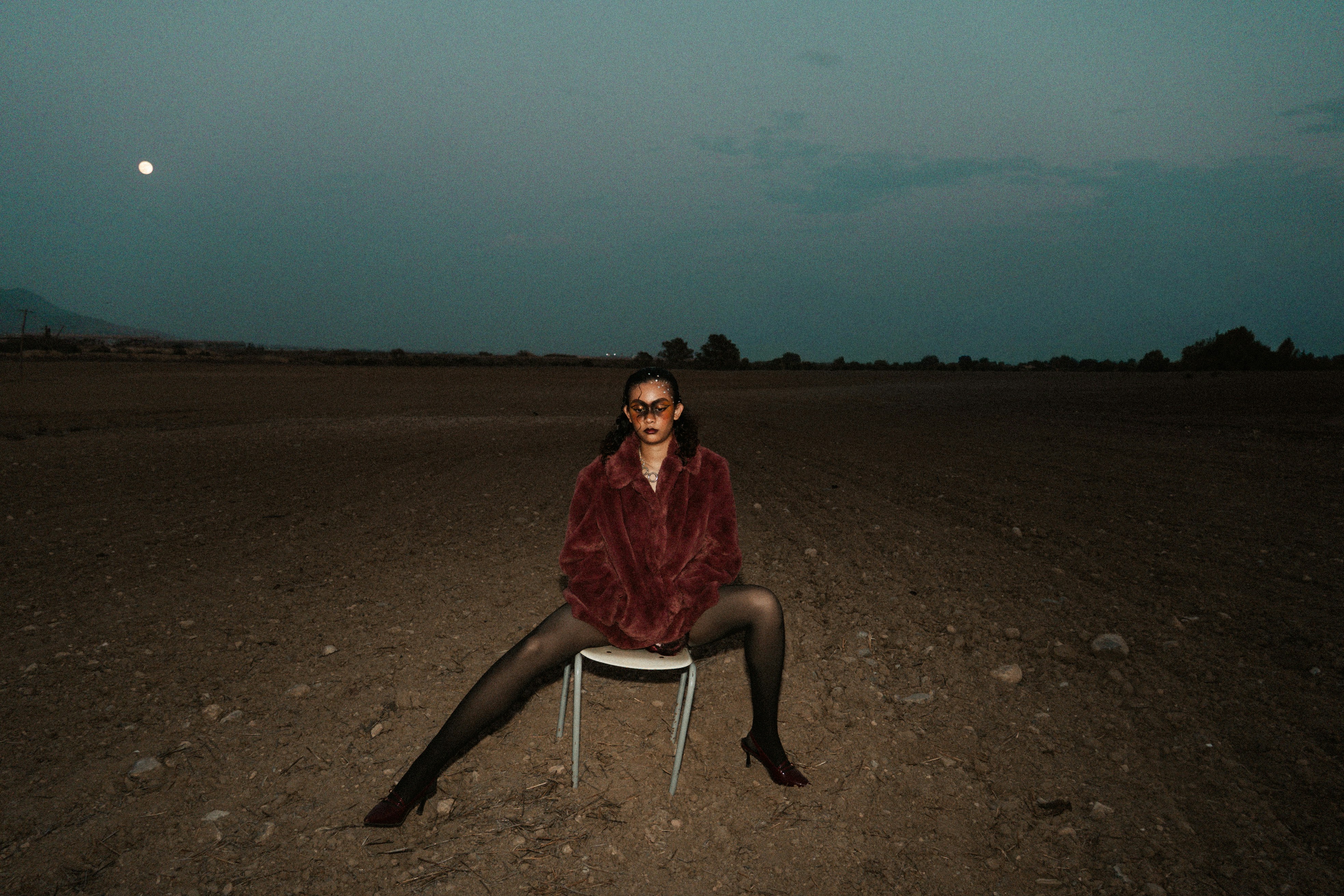 Femme assise sur une chaise dans un paysage désolé la nuit
