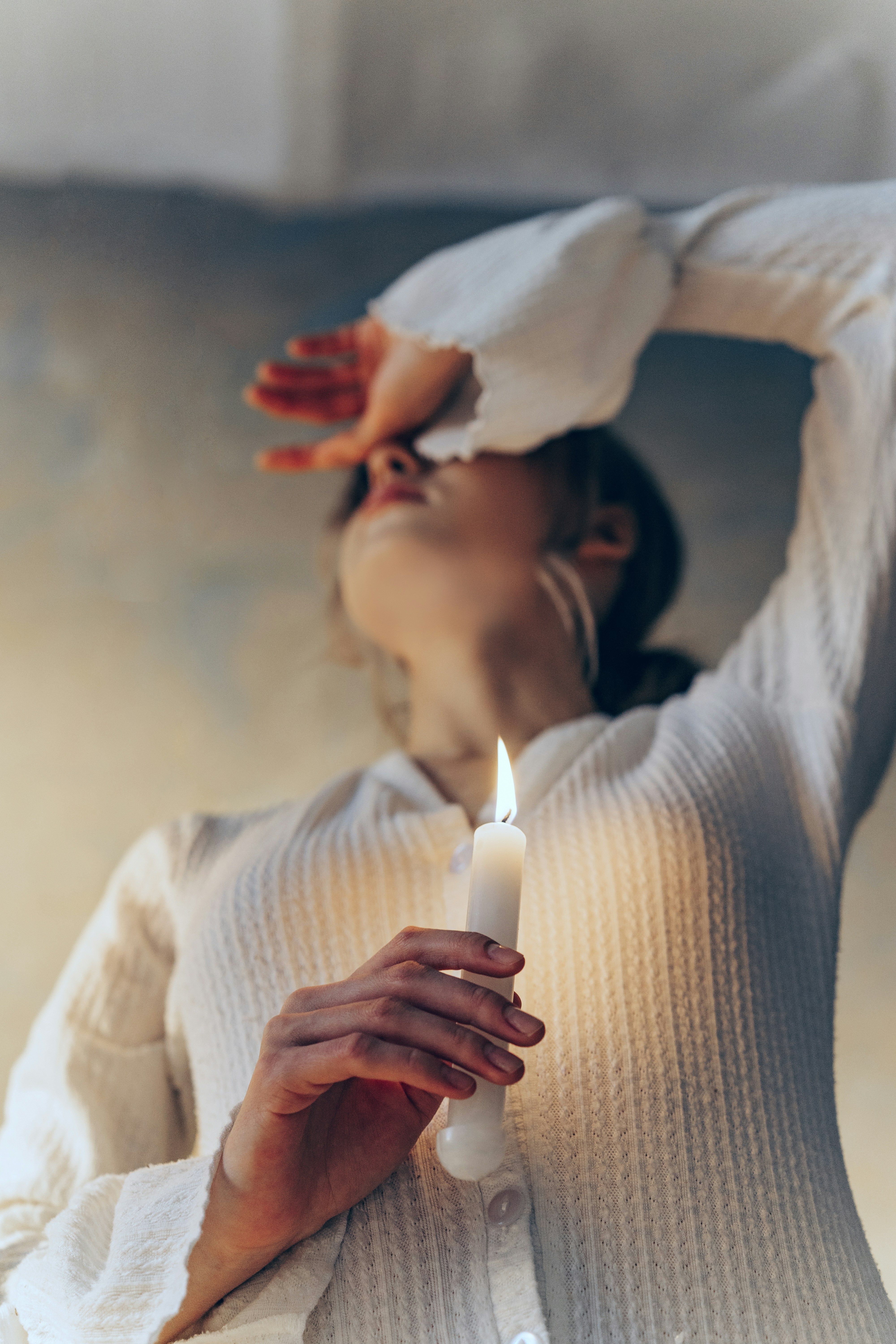 Woman holding a lit candle shielding her eyes