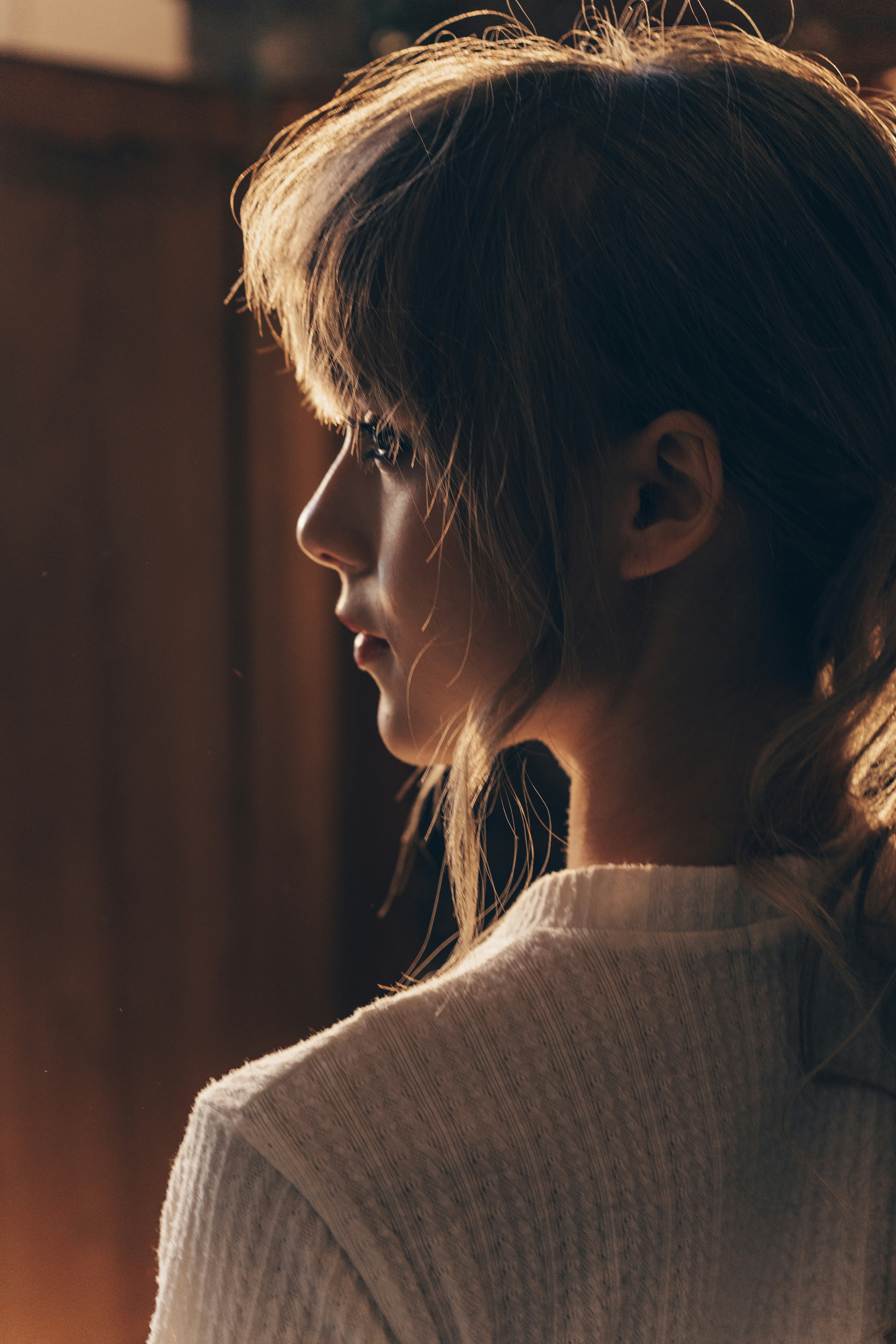 Young woman with bangs and ponytail in profile.