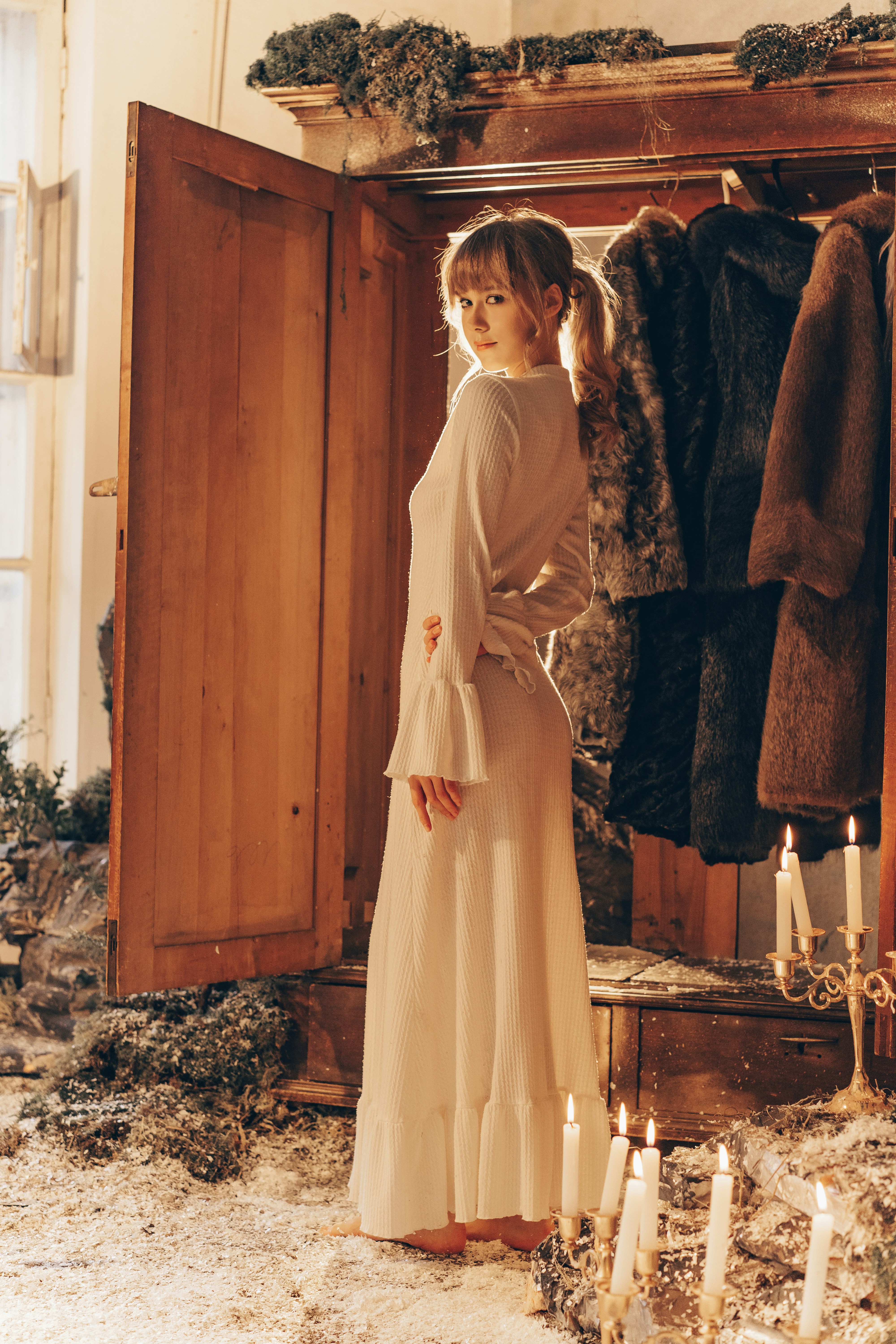 Woman in a long dress stands by an open wardrobe
