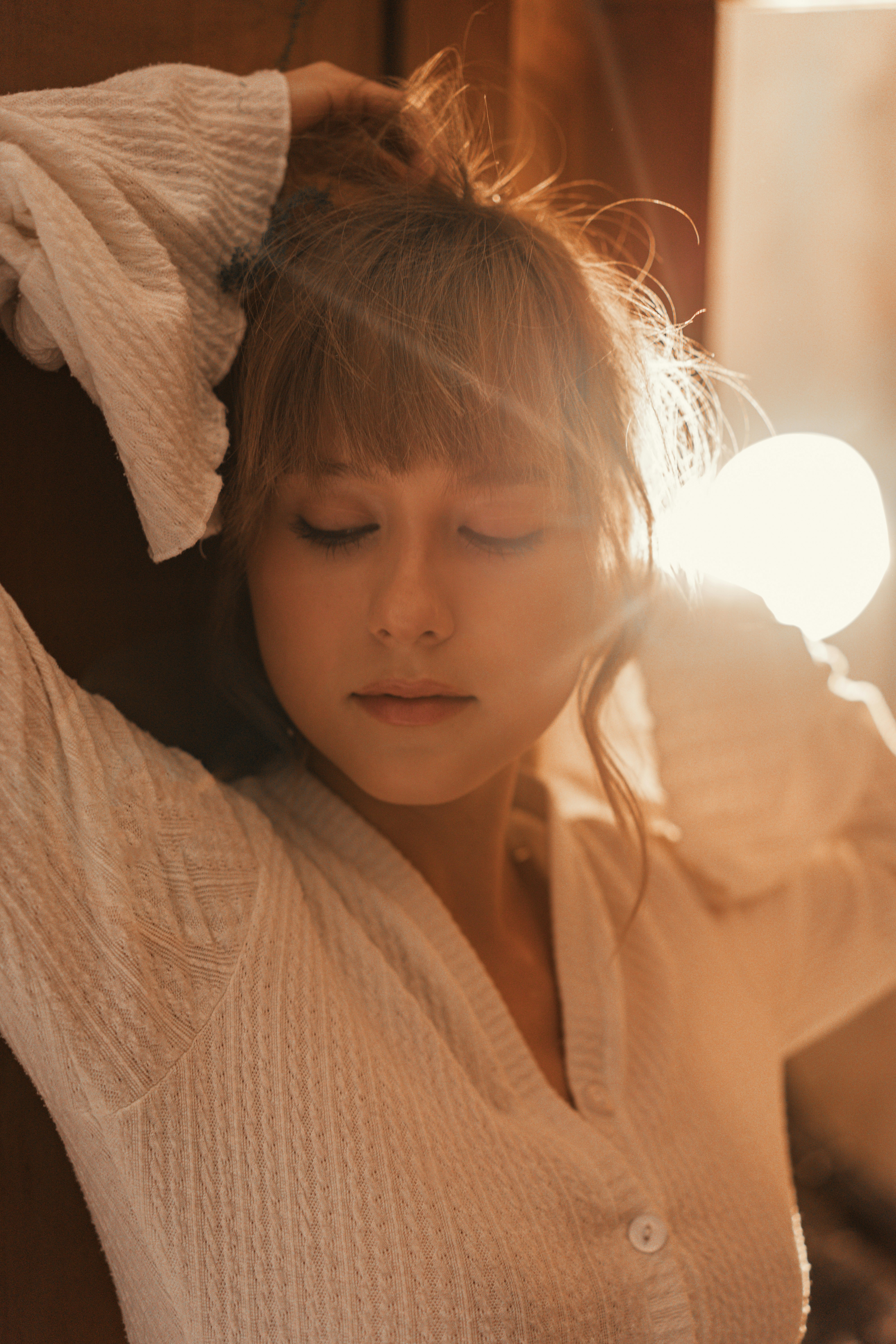 Woman with eyes closed in warm, soft light.