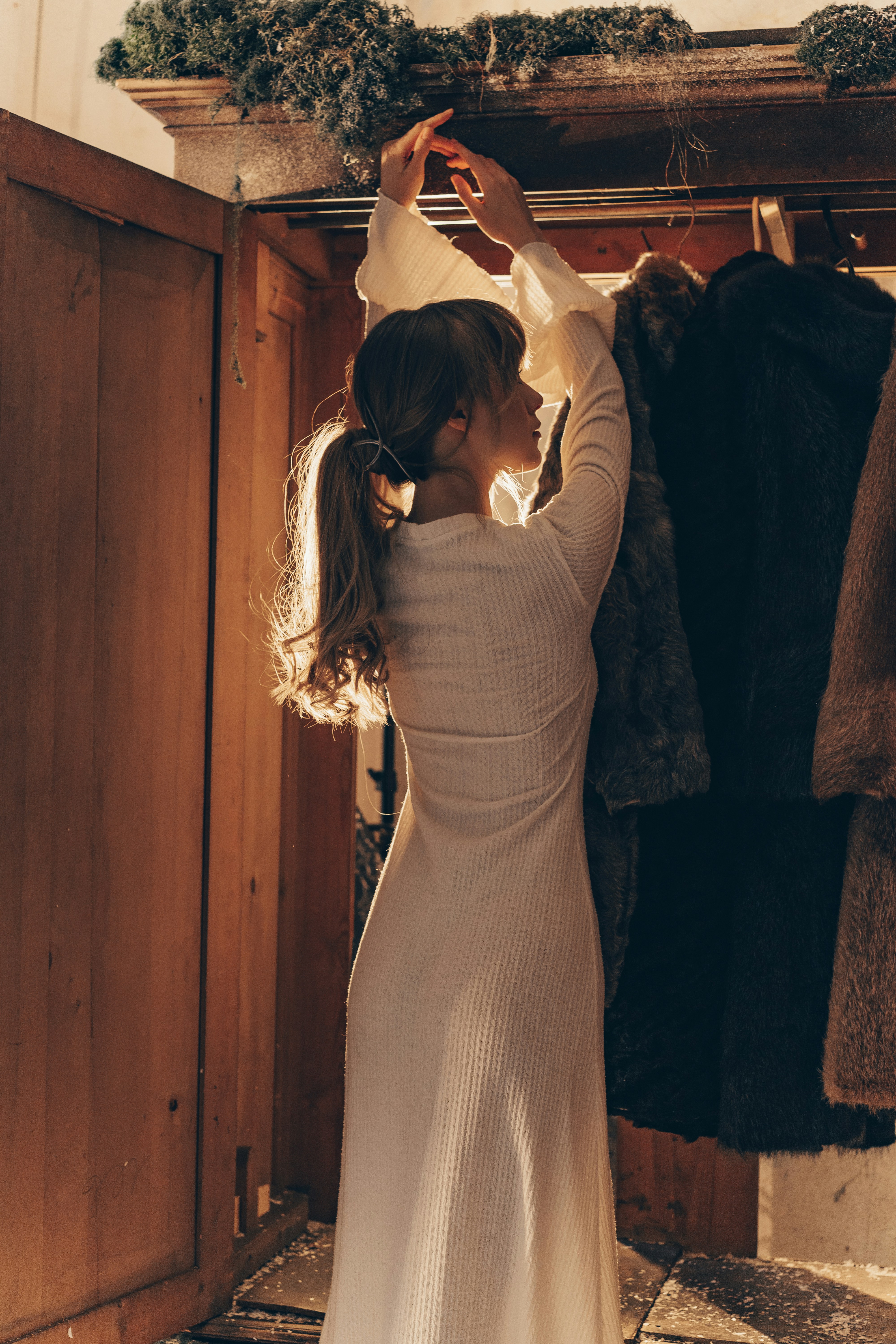 Woman selecting clothes from a wooden wardrobe.