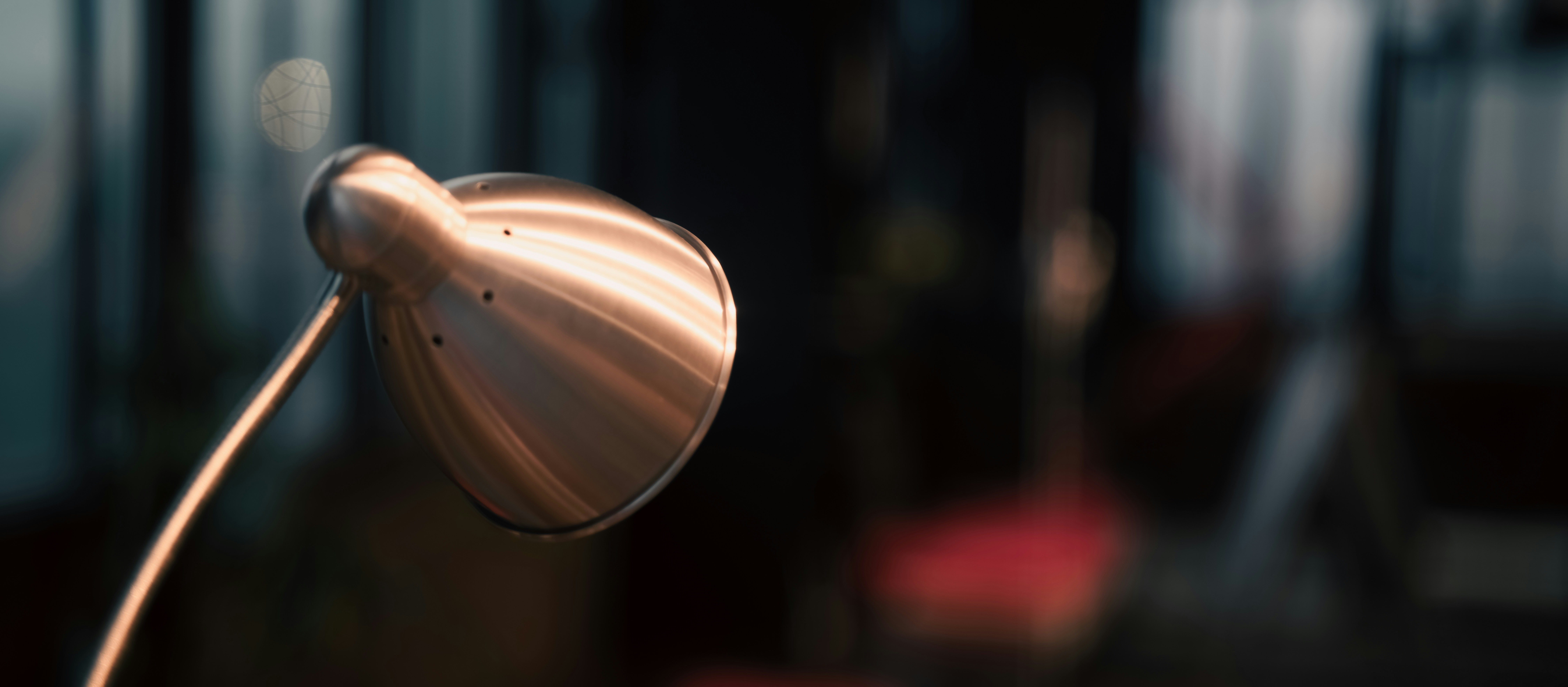 Close-up of a metallic desk lamp with blurred background.
