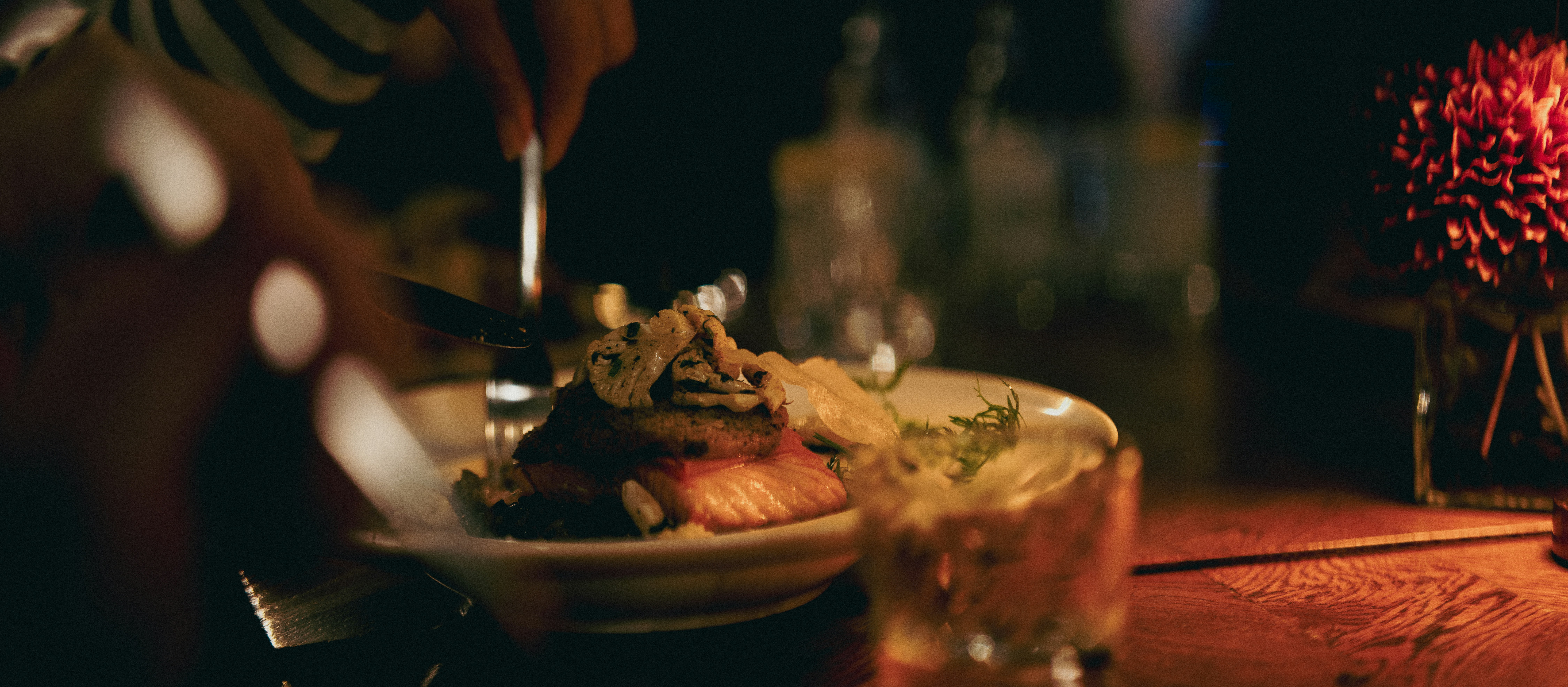 A person eating a plated meal with a drink.
