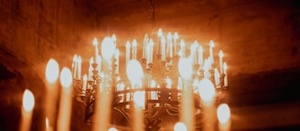 Many lit candles on a chandelier in darkness