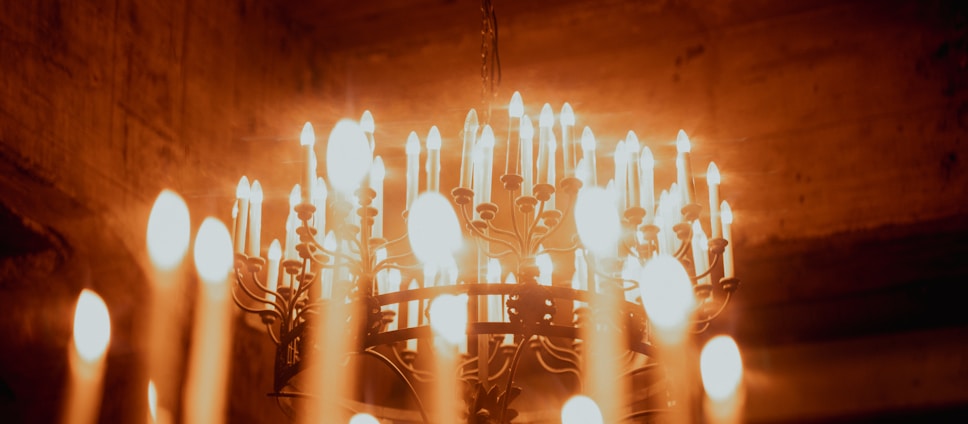 Many lit candles on a chandelier in darkness