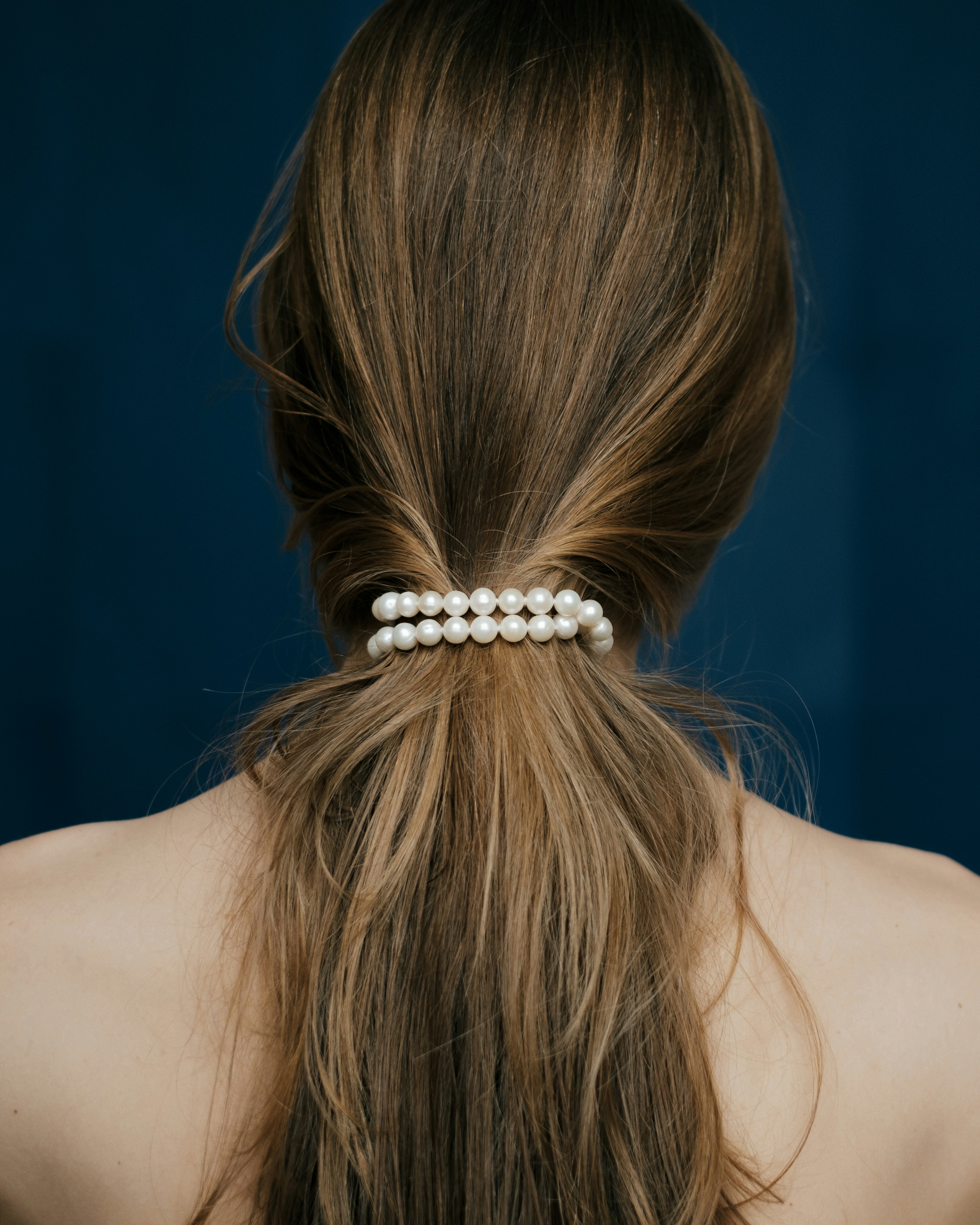 Woman's long brown hair tied with pearl bracelet