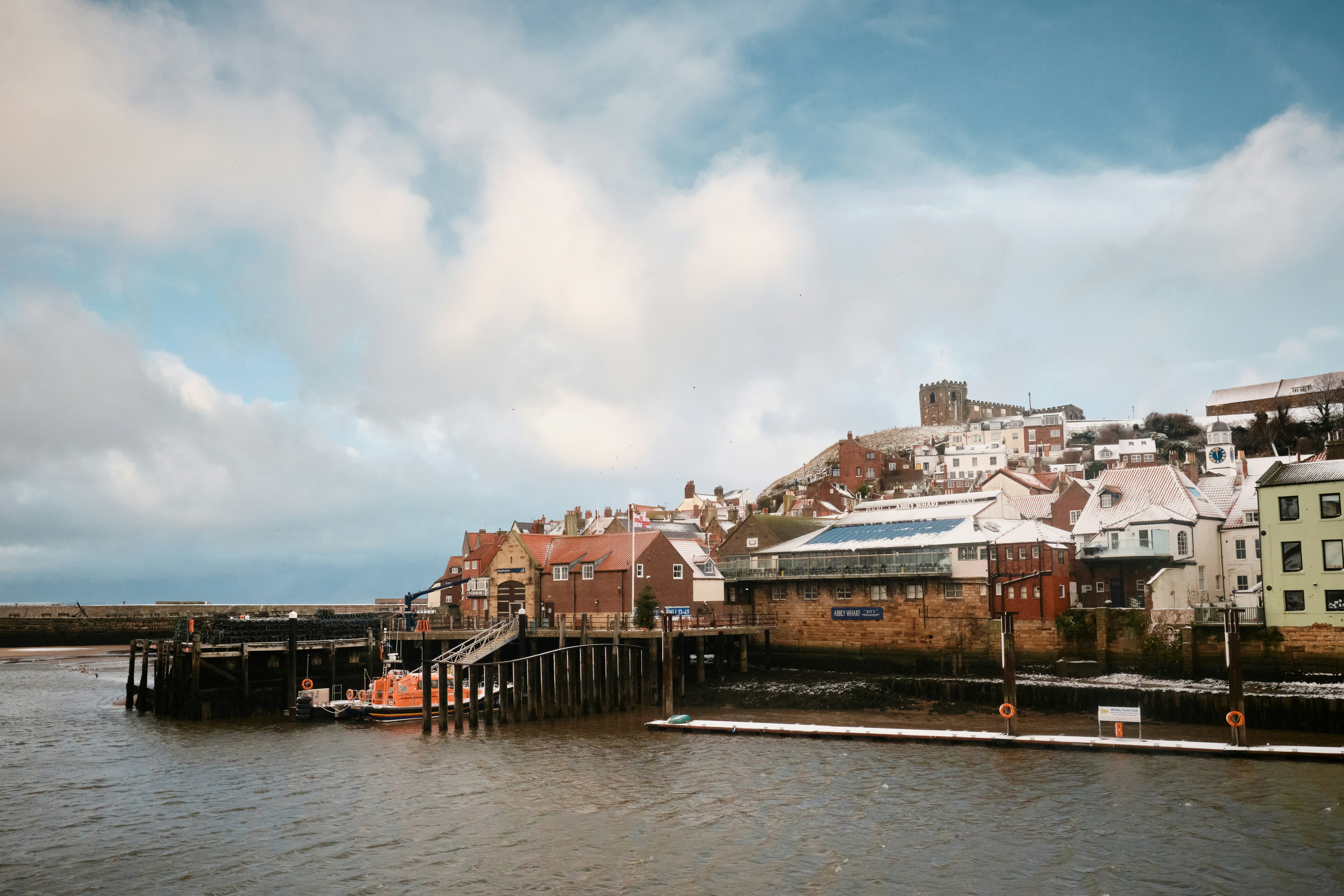 مبانٍ مغطاة بالثلوج تصطف على الواجهة البحرية مع سماء ملبدة بالغيوم.