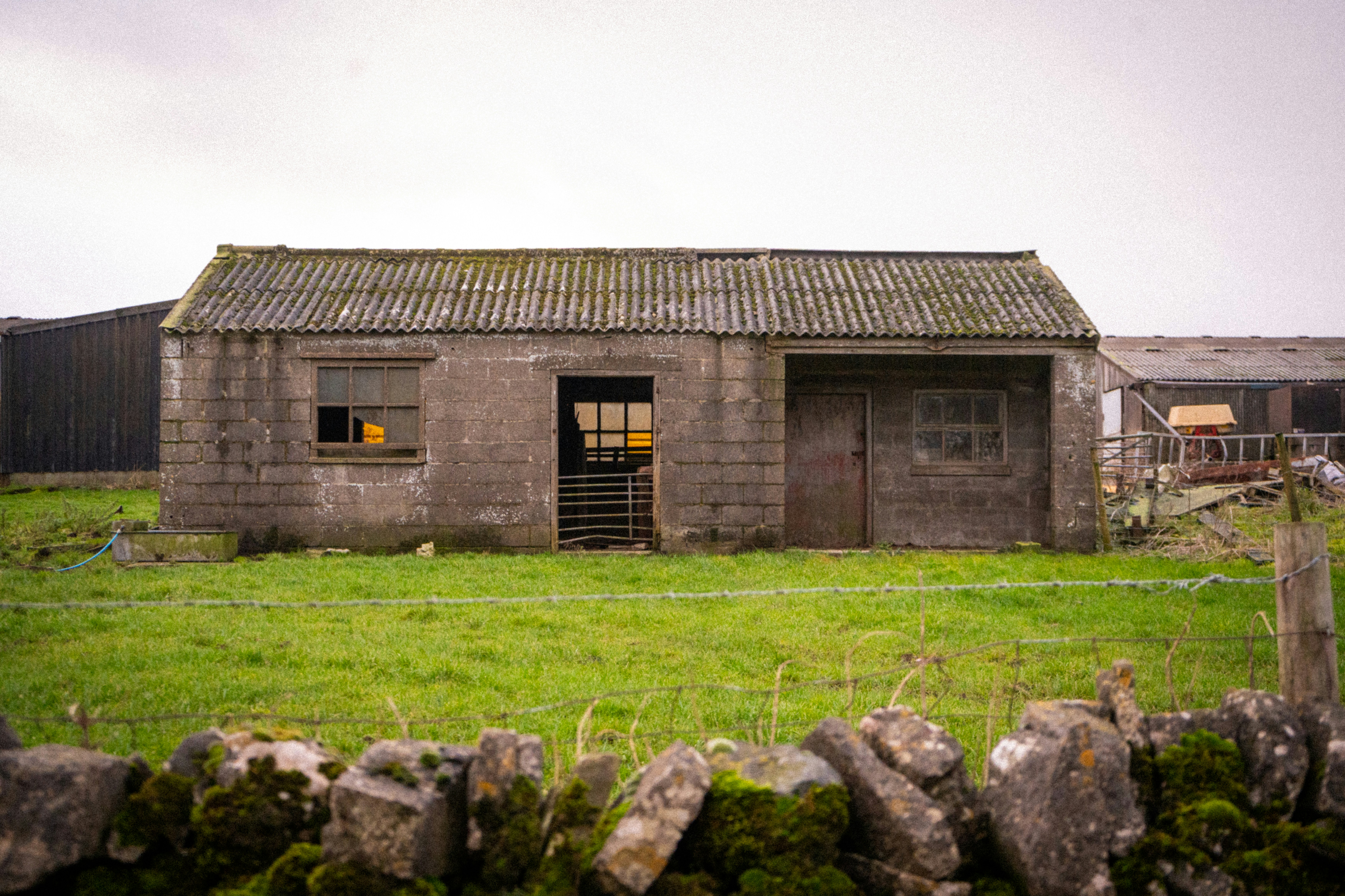 Old stone shed in a grassy field.
