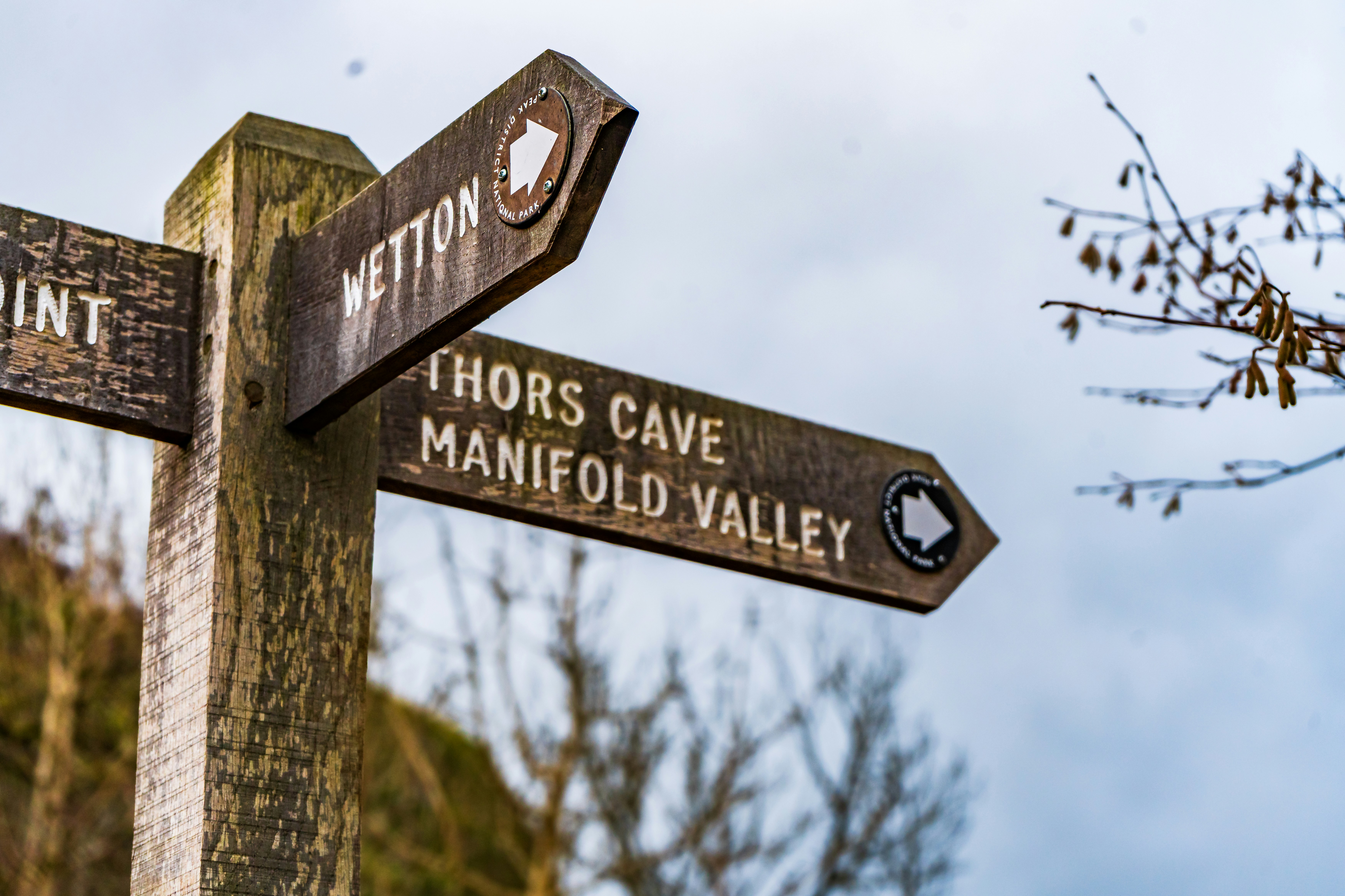 Wooden signpost pointing to thors cave and manifold valley
