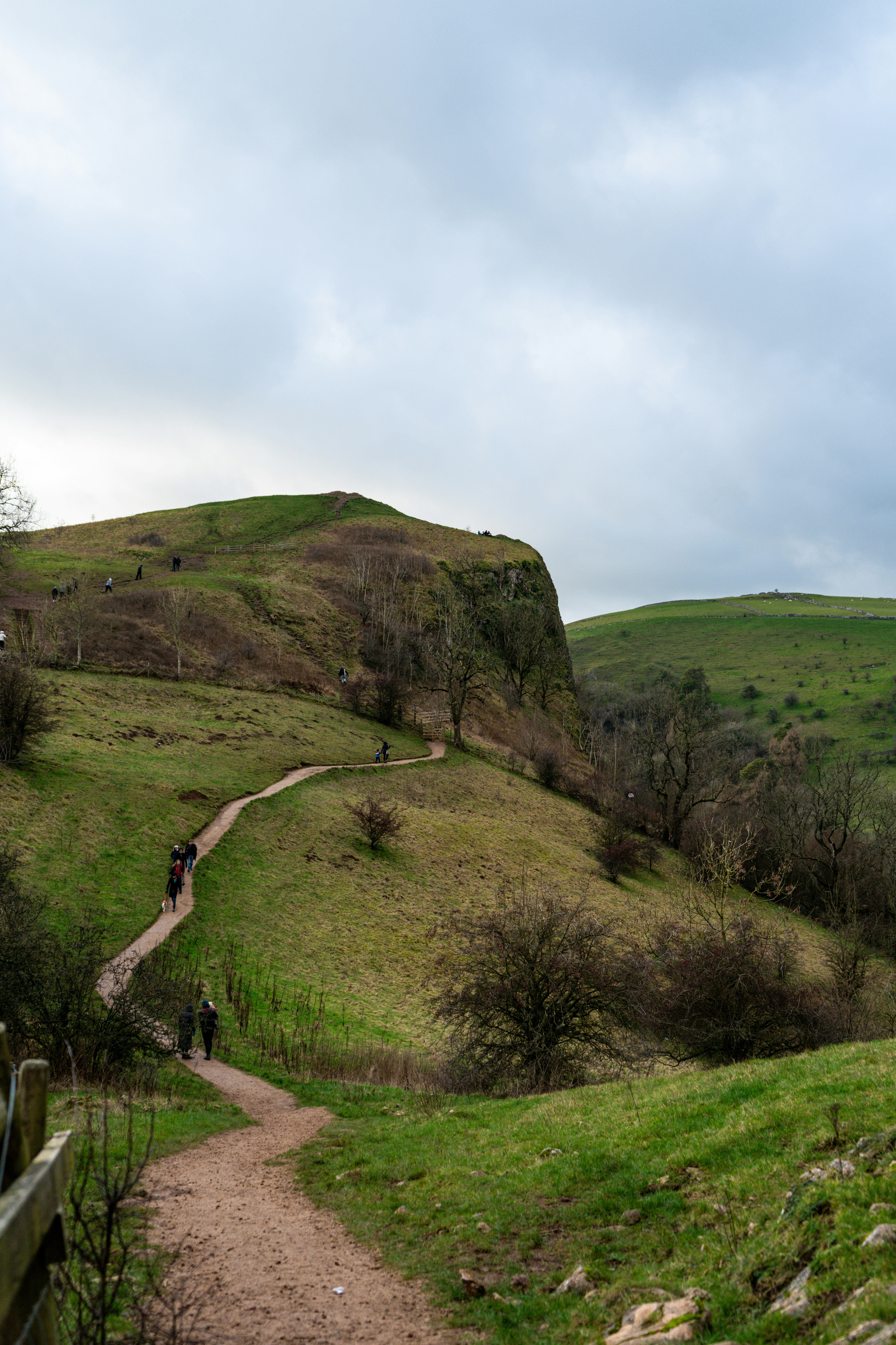 Hikers on a trail through rolling green hills.