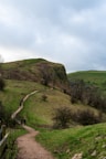 Hikers on a trail through rolling green hills.