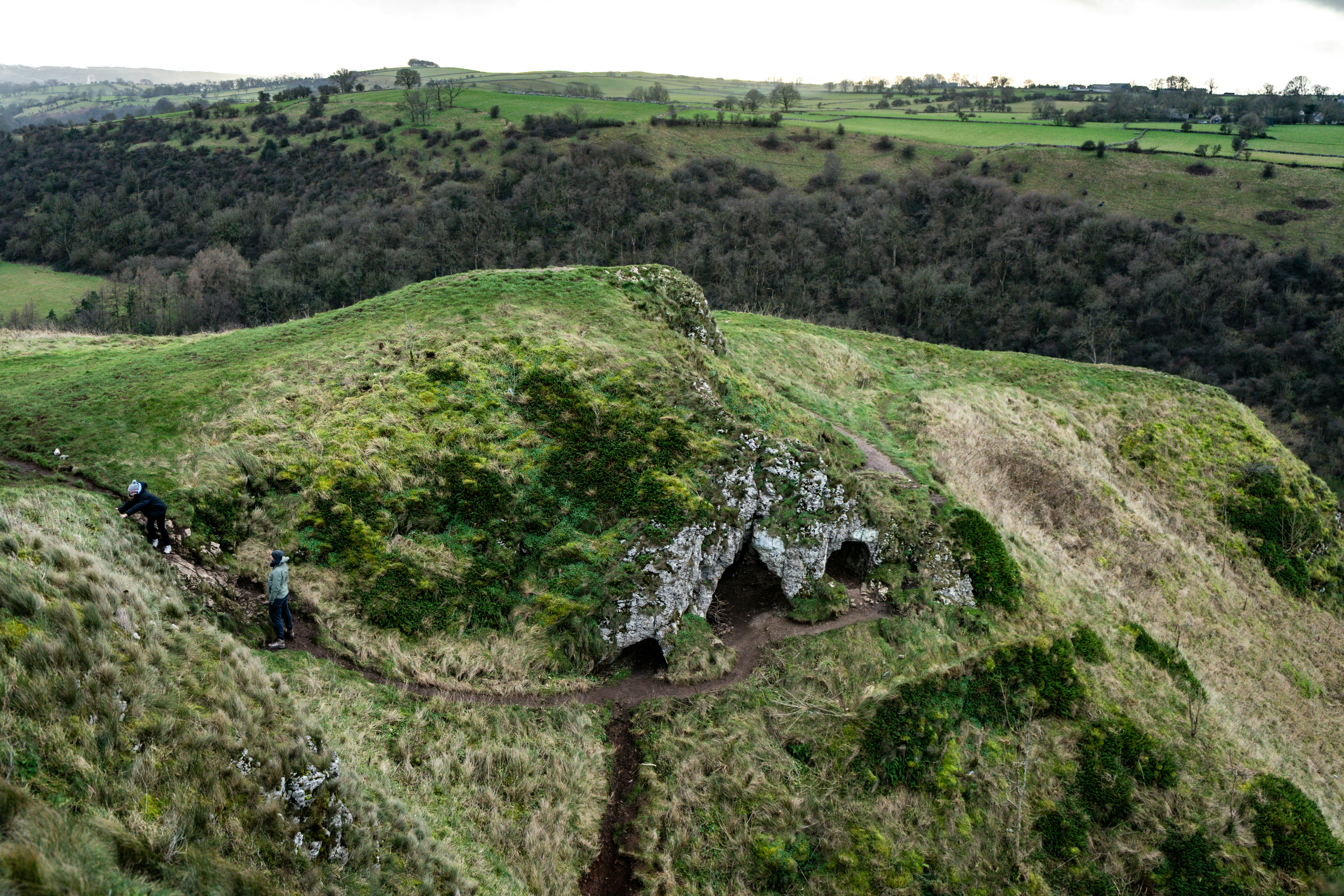 Green rolling hills with a cave entrance