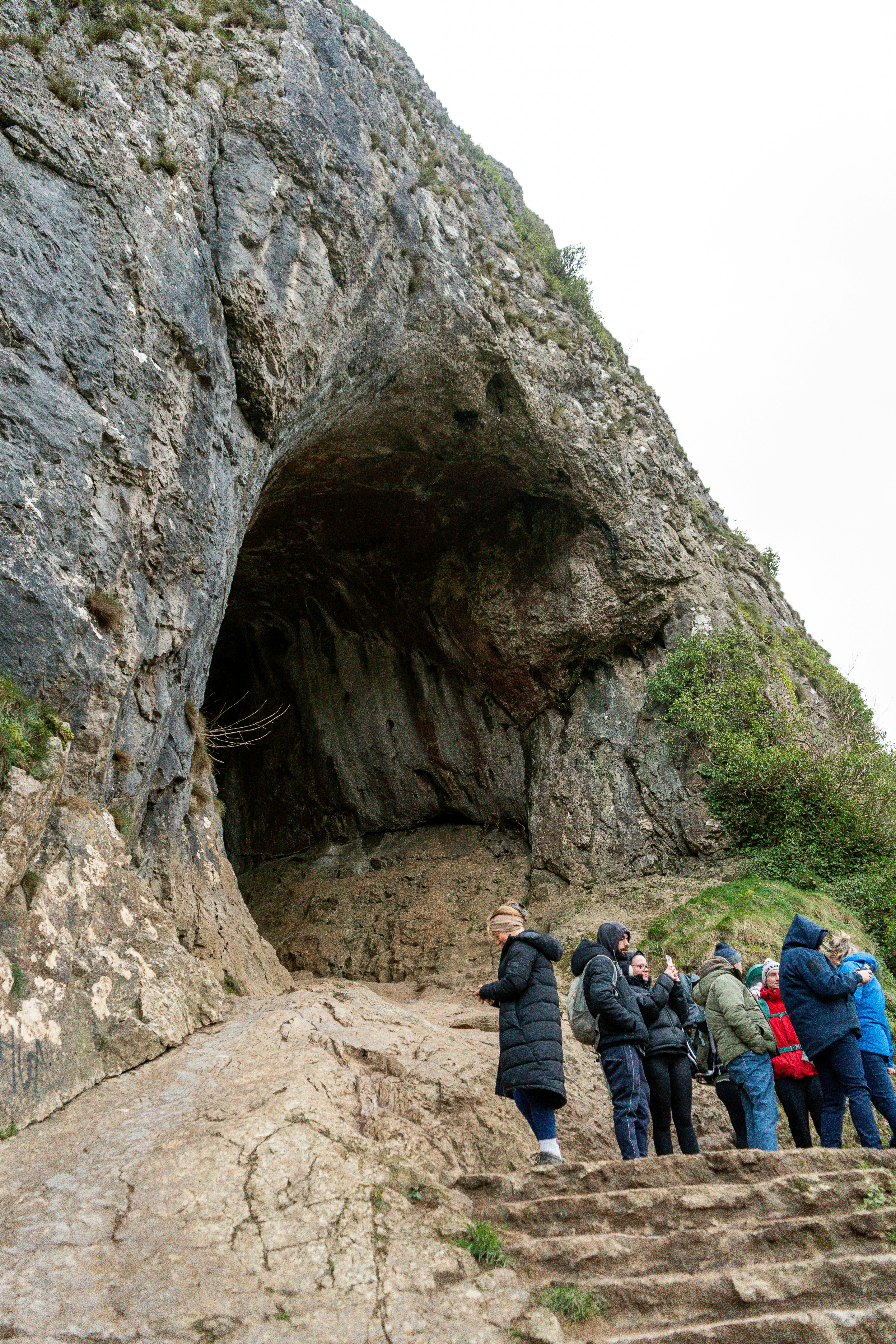 People standing at the entrance of a large cave.