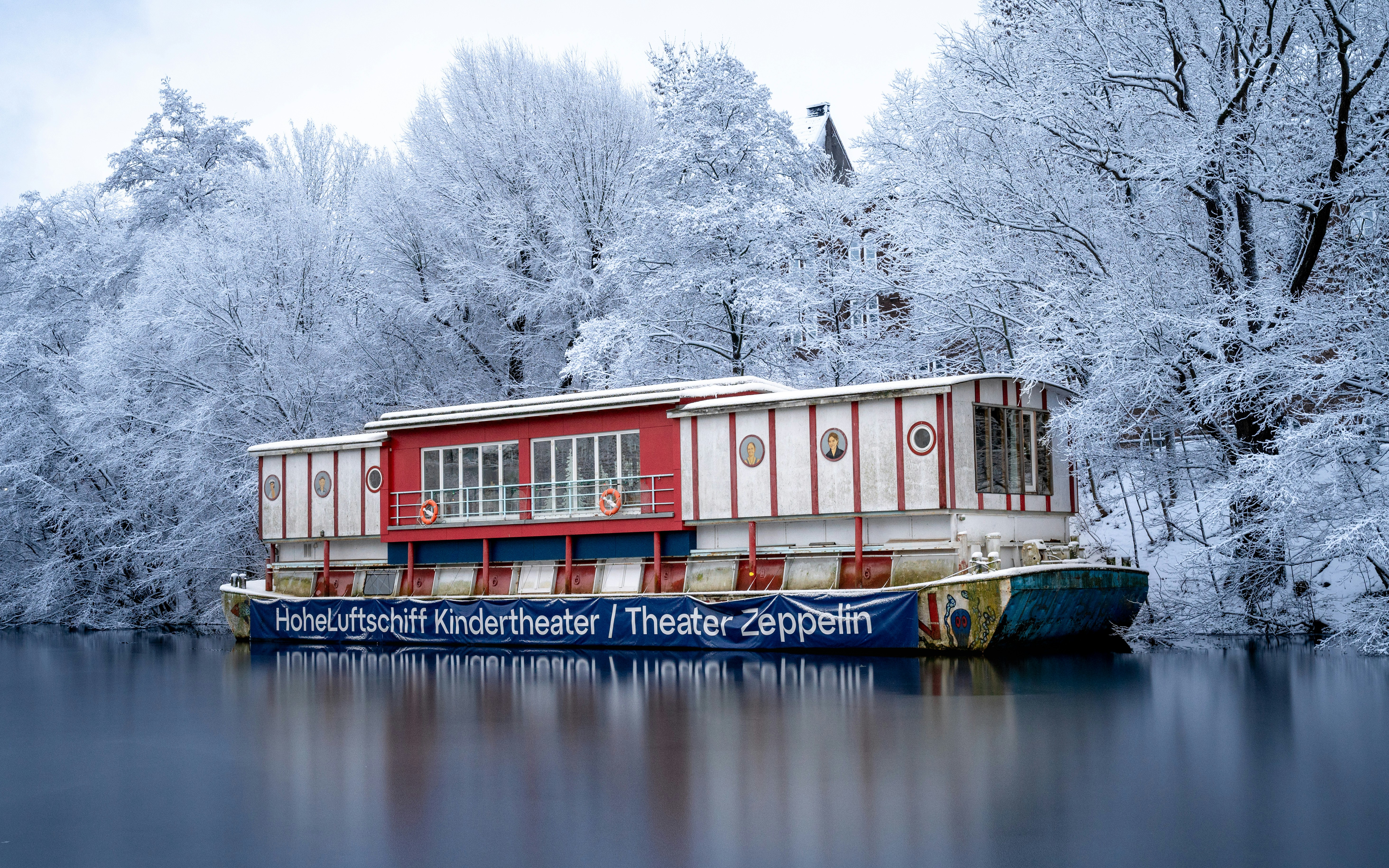 A houseboat with red accents on a calm lake.