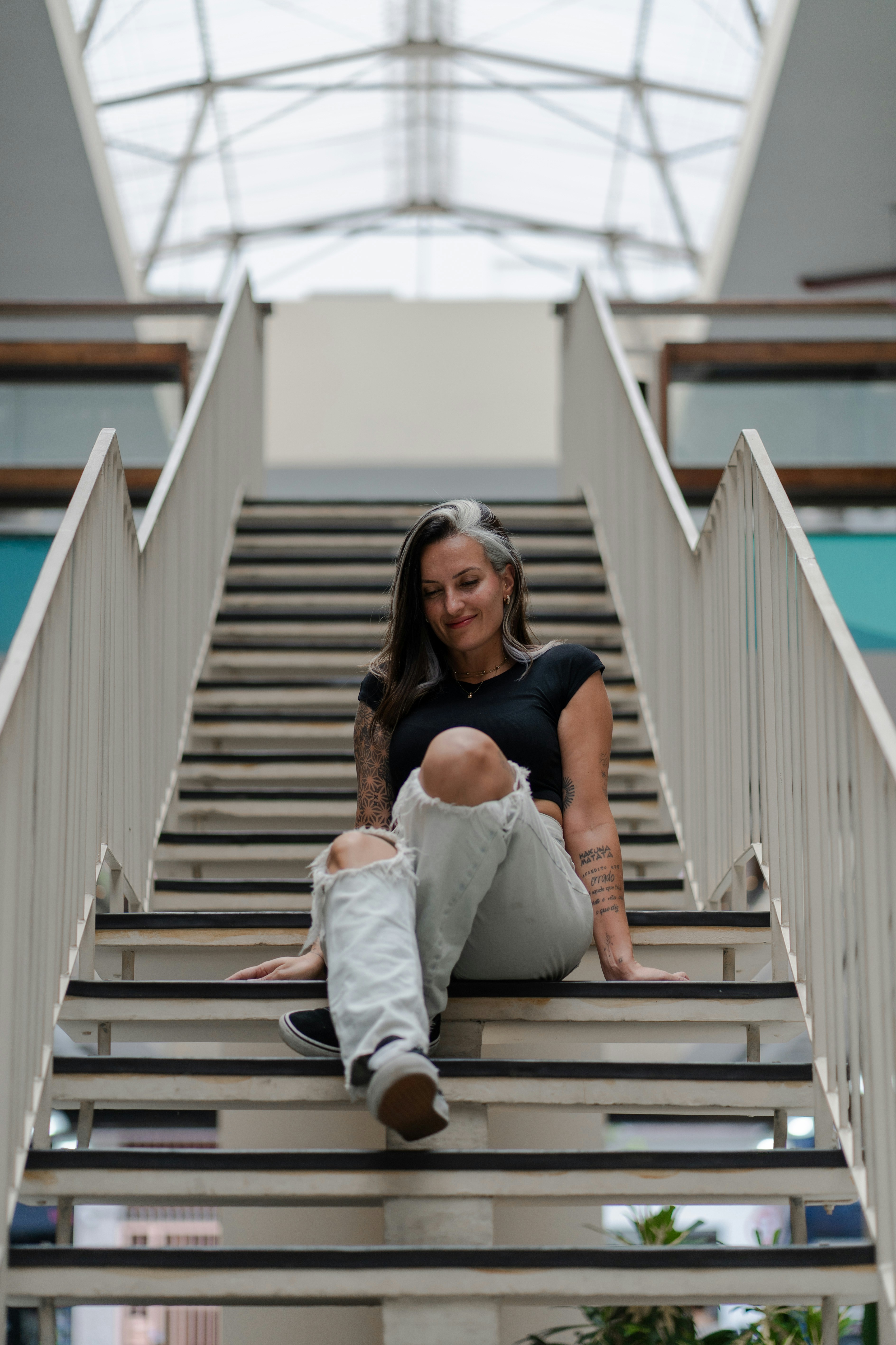 A woman with tattoos sits on a staircase.