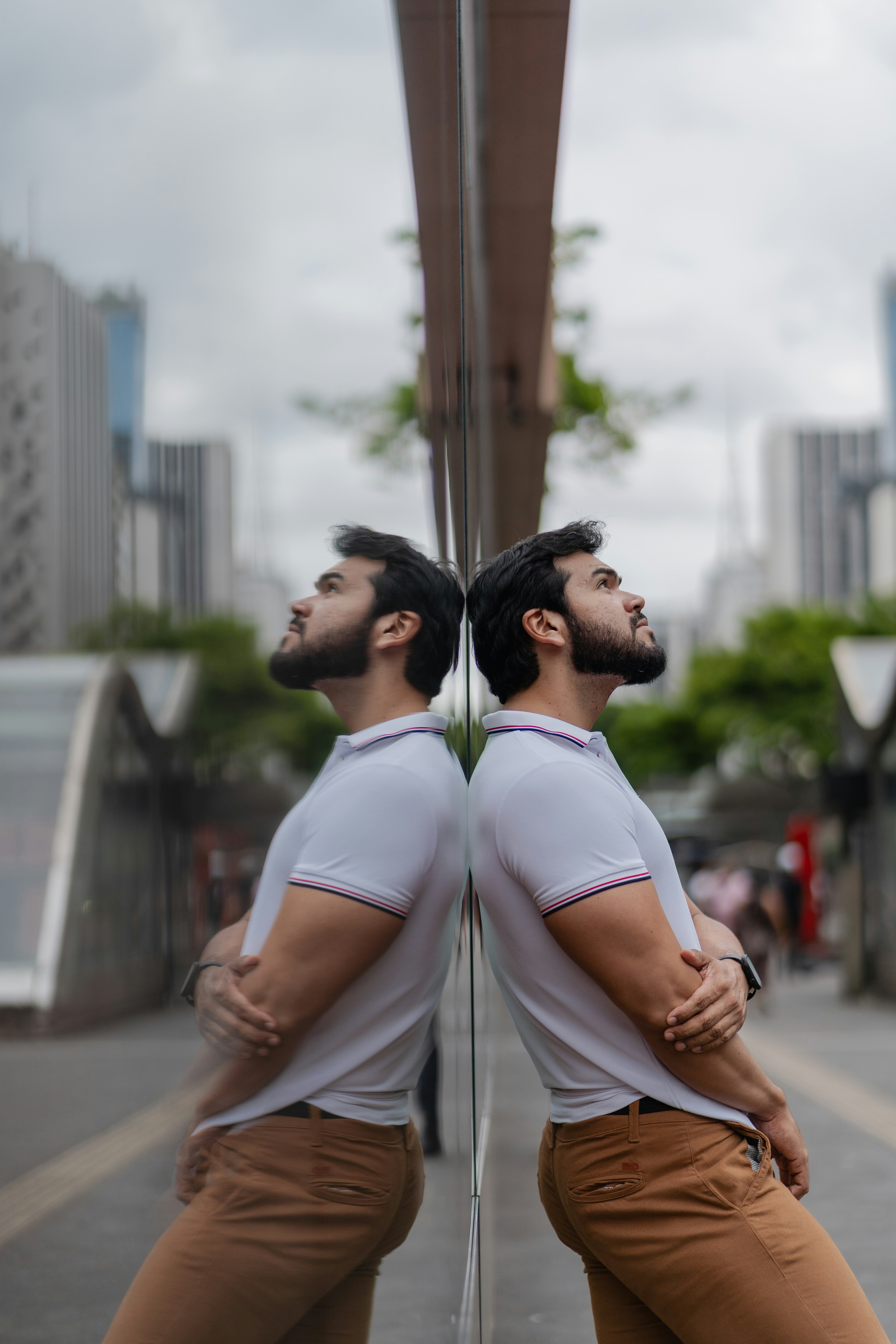 Man leaning against reflective surface with city buildings