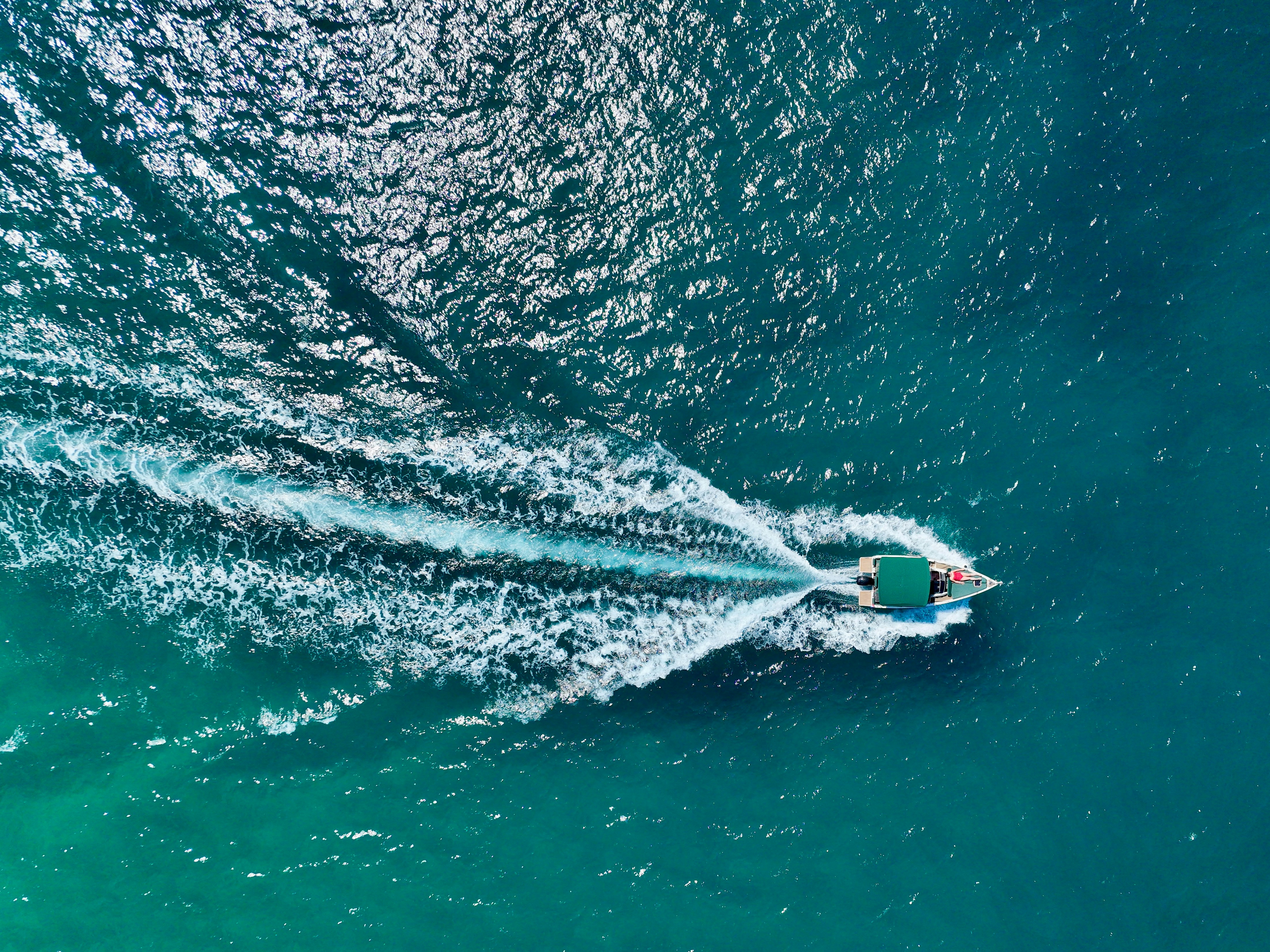 A boat speeding through clear turquoise ocean water.