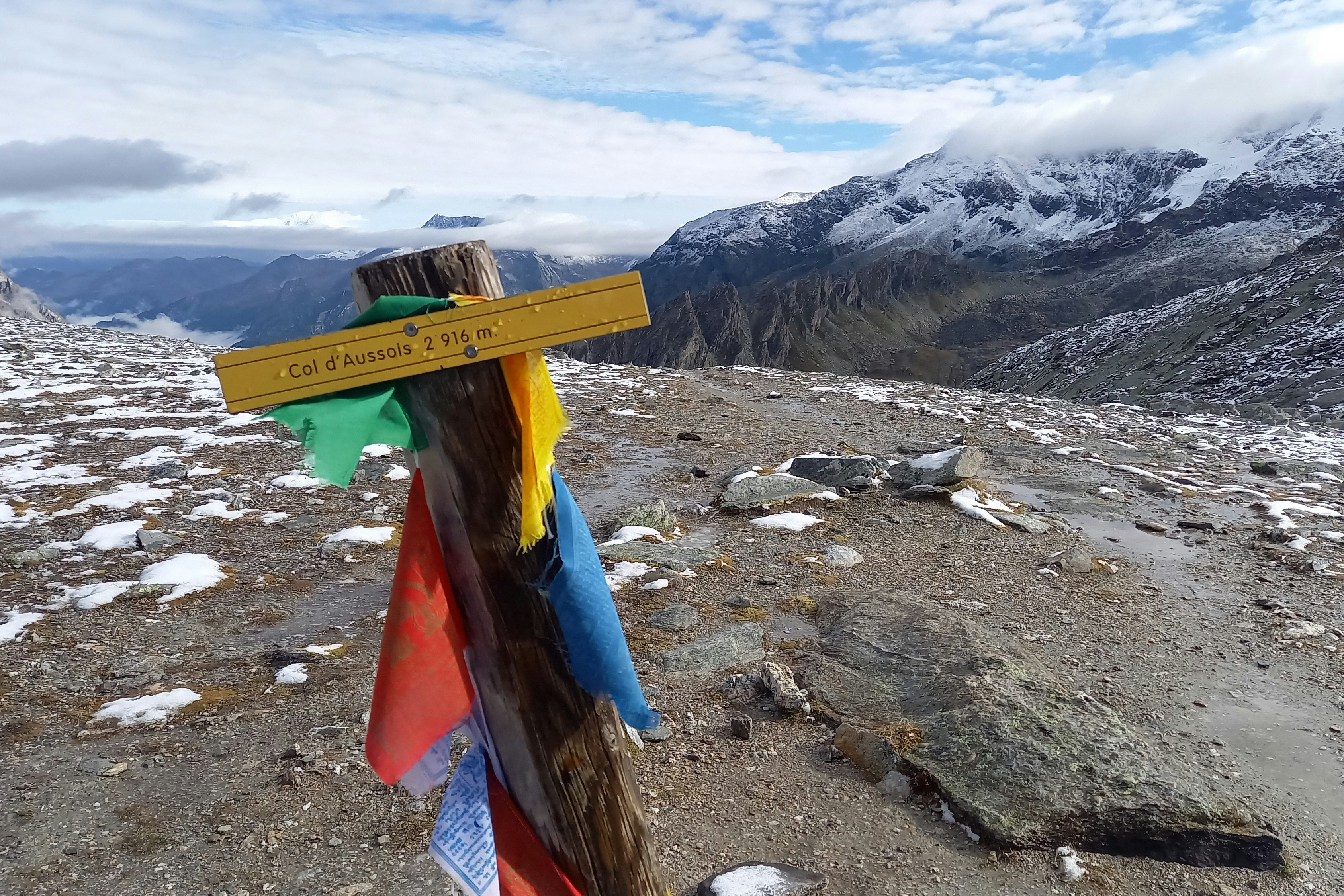 Wooden post with prayer flags and mountain view.