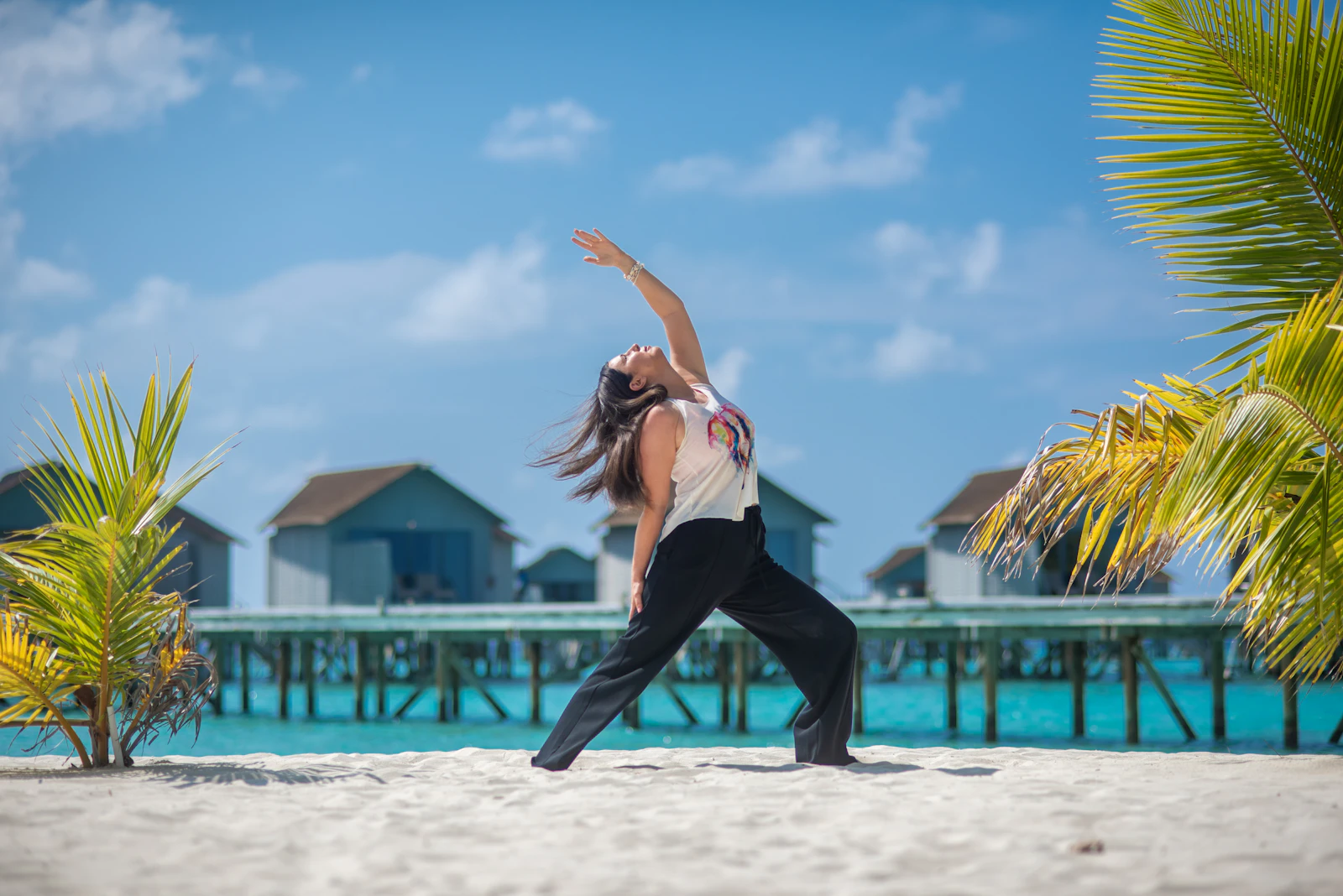A person practising yoga on the sand beside the ocean