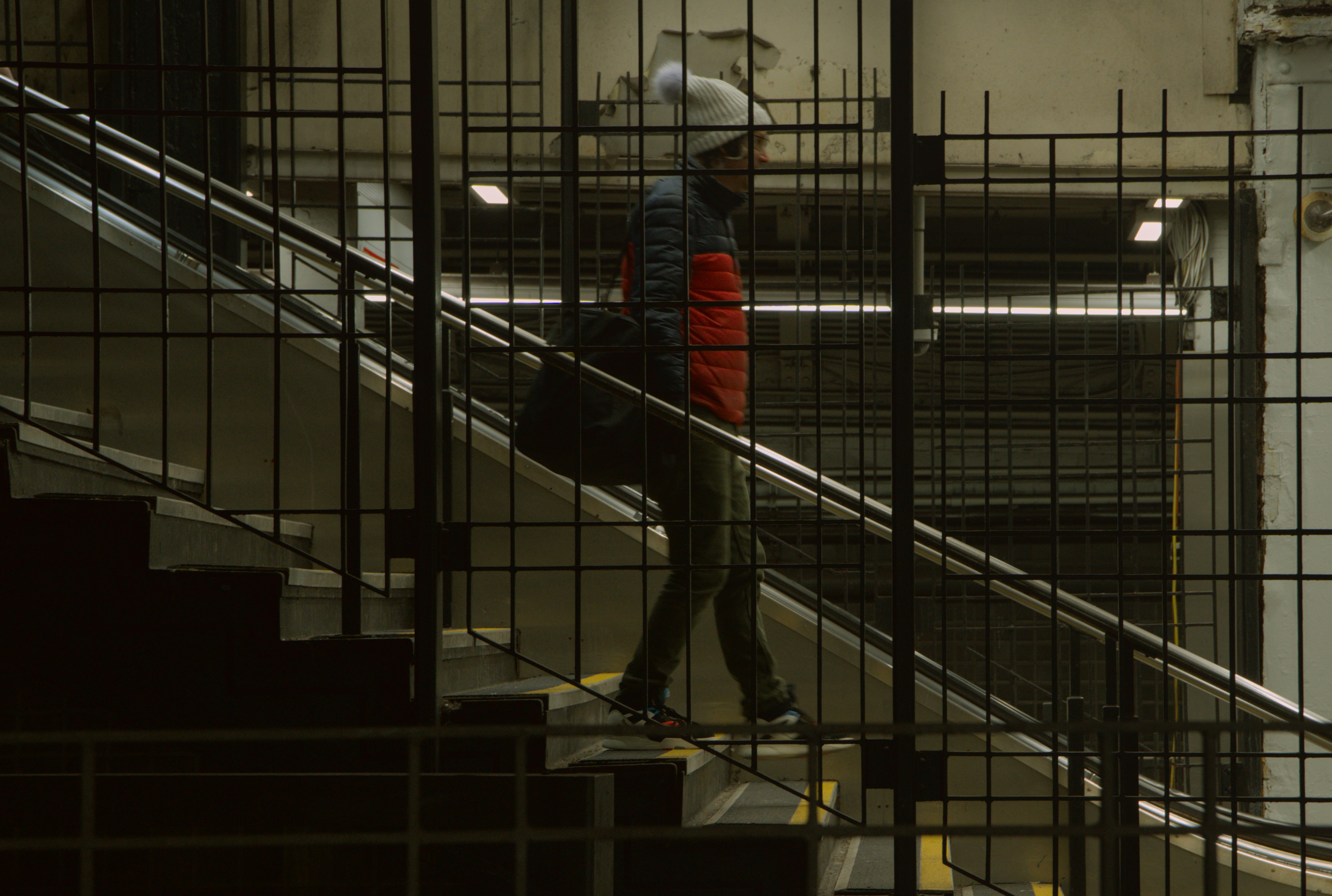 Man in puffer jacket walks down stairs.