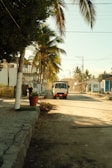 A truck drives down a sunny, dusty street.