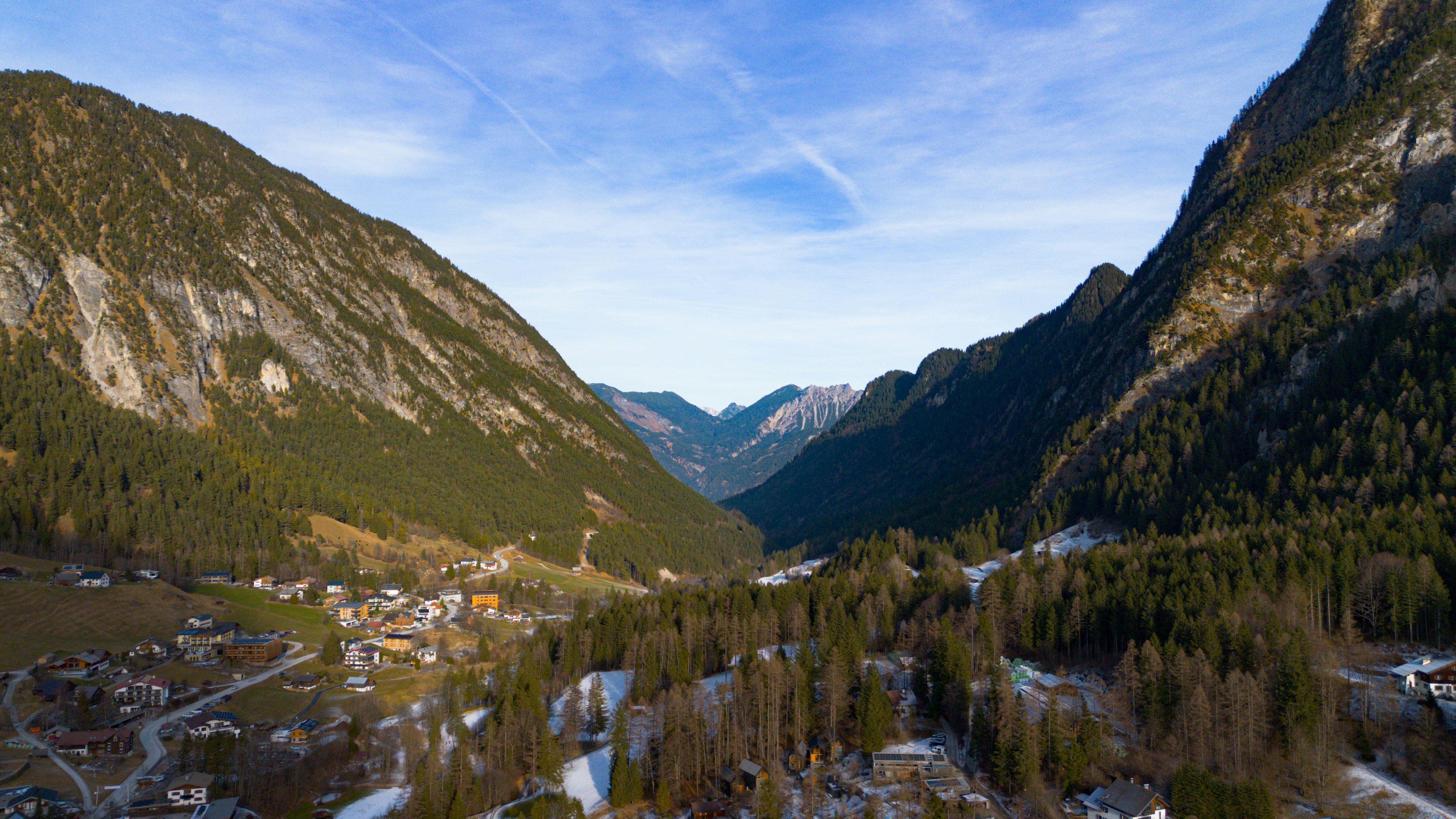 Snowy valley with a small village and forested mountains