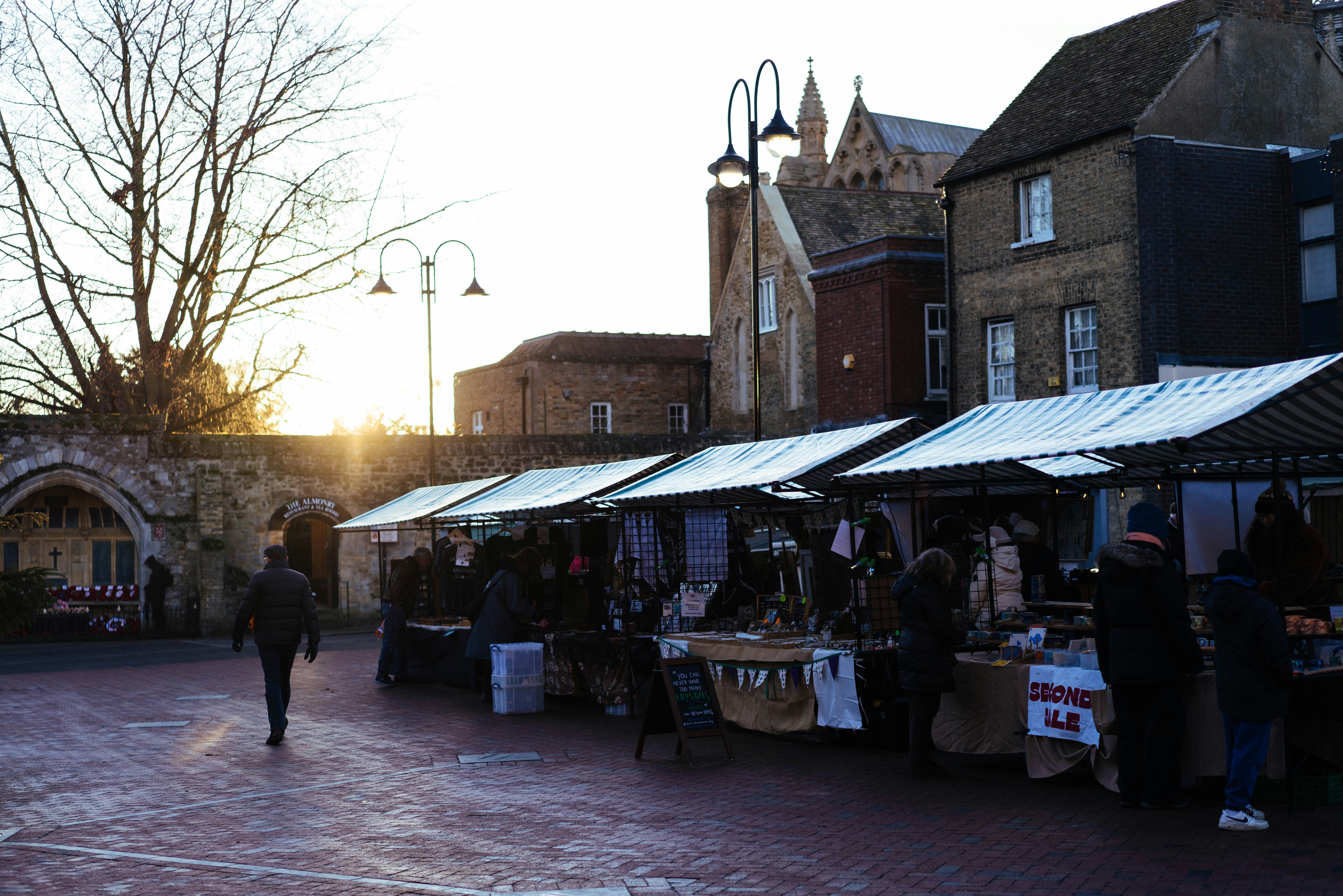 Outdoor market stalls with people browsing goods and buildings