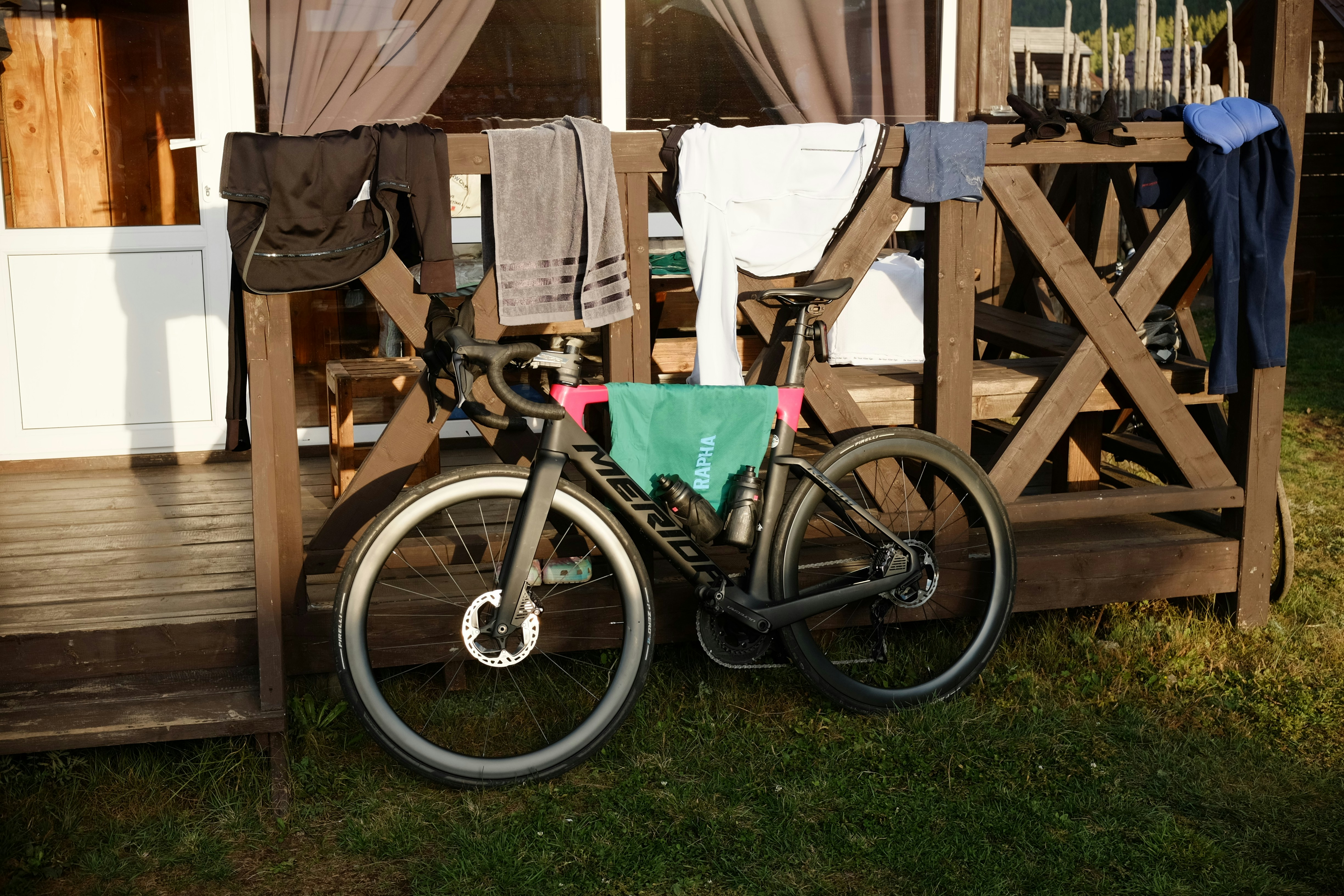 Bicycle leaning against wooden railing with laundry drying