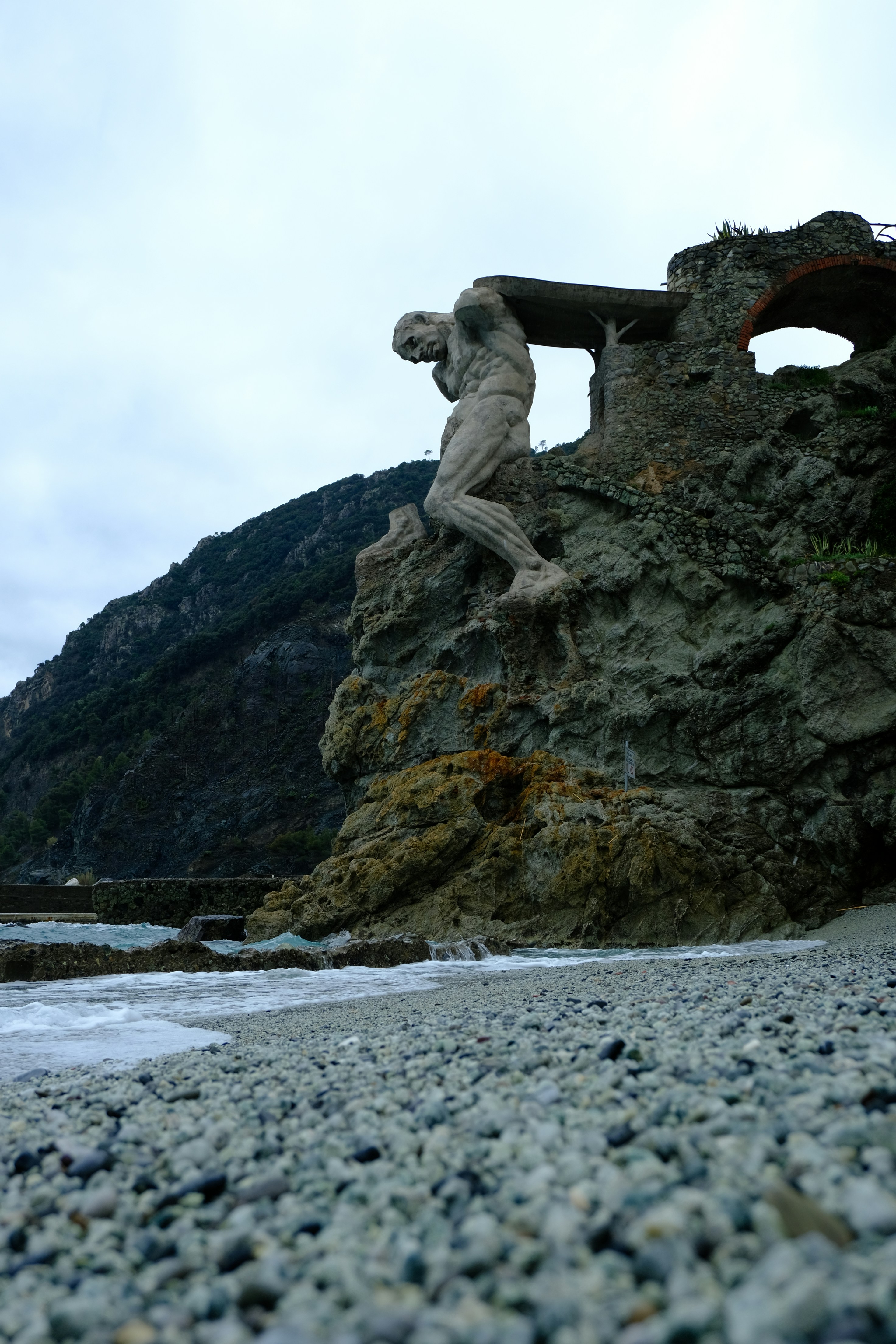 Steinskulptur des Menschen auf einer Klippe mit Blick auf den Ozean