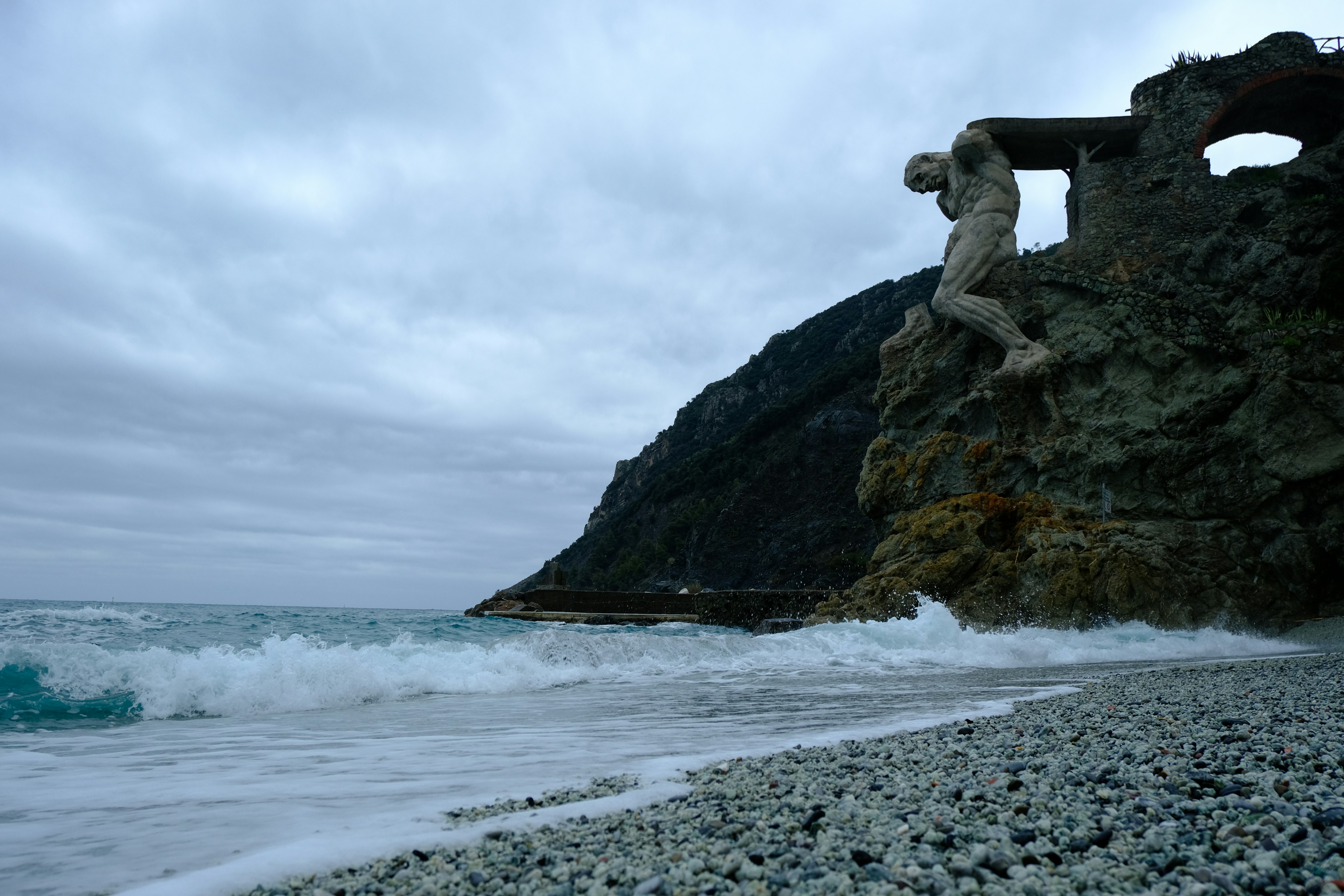 Statue on cliff overlooking stormy ocean waves