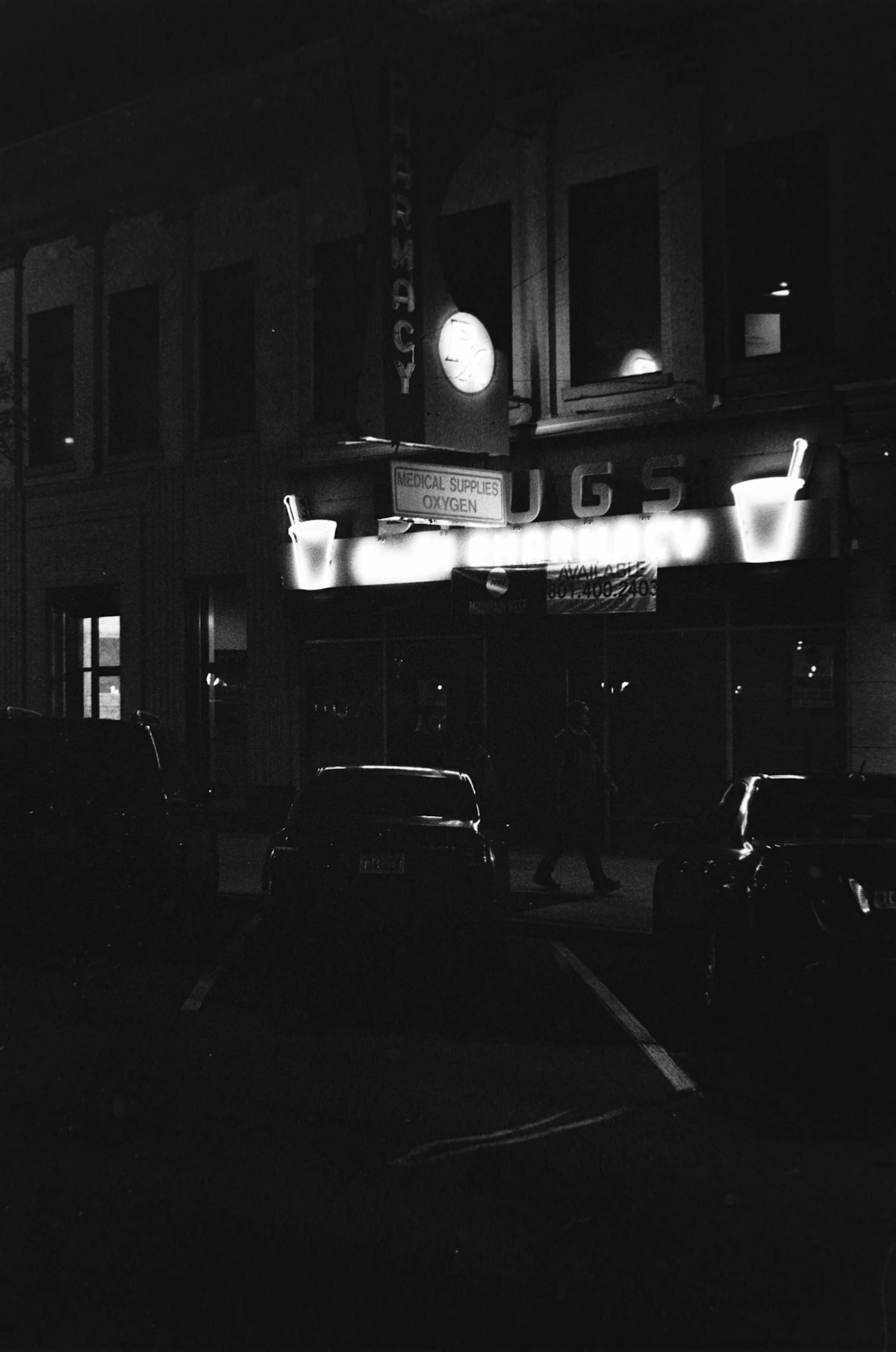 An illuminated pharmacy at night representing access to medicines and advice
