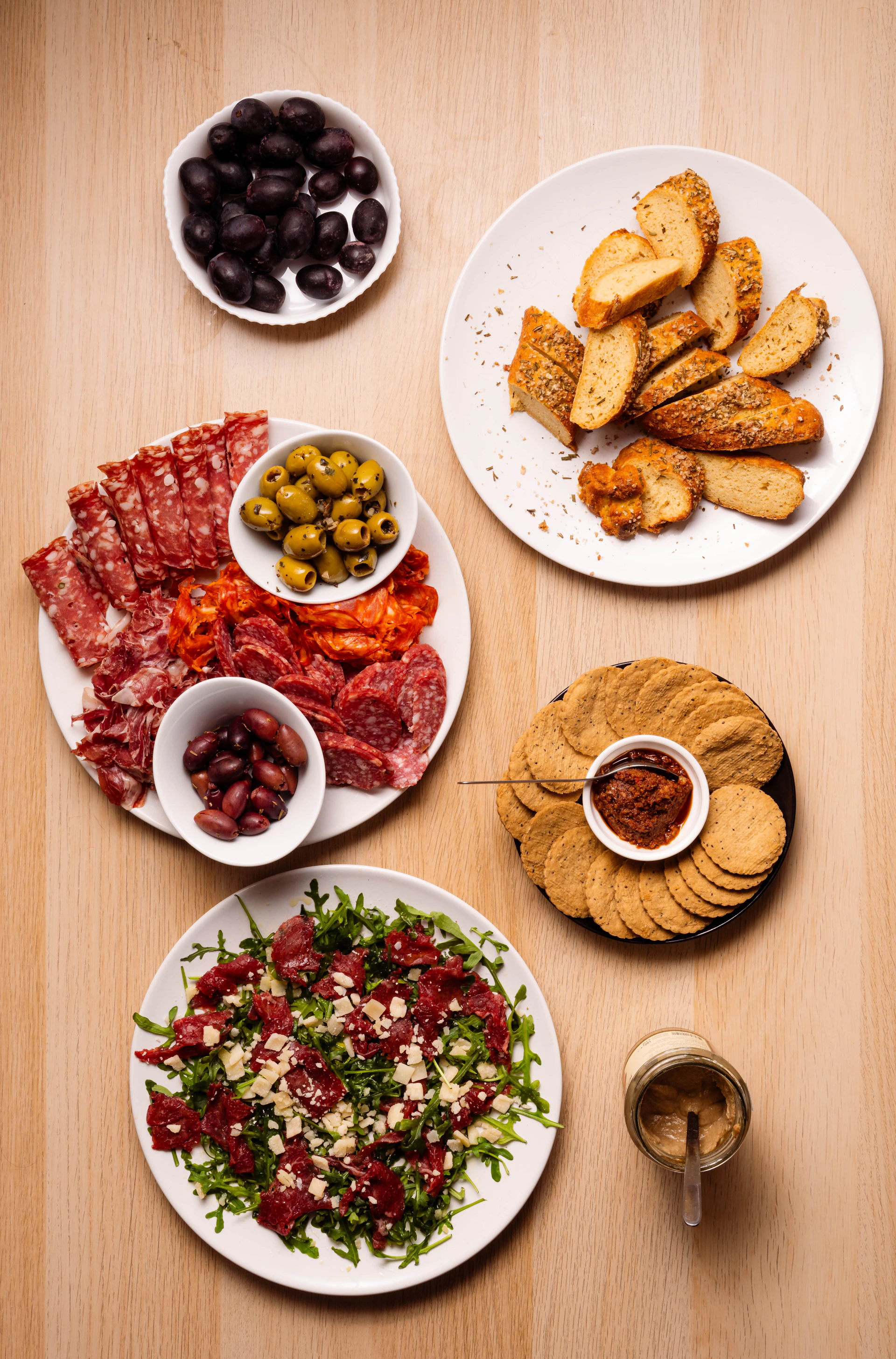 Assortment of cured meats, olives, crackers, and salad.