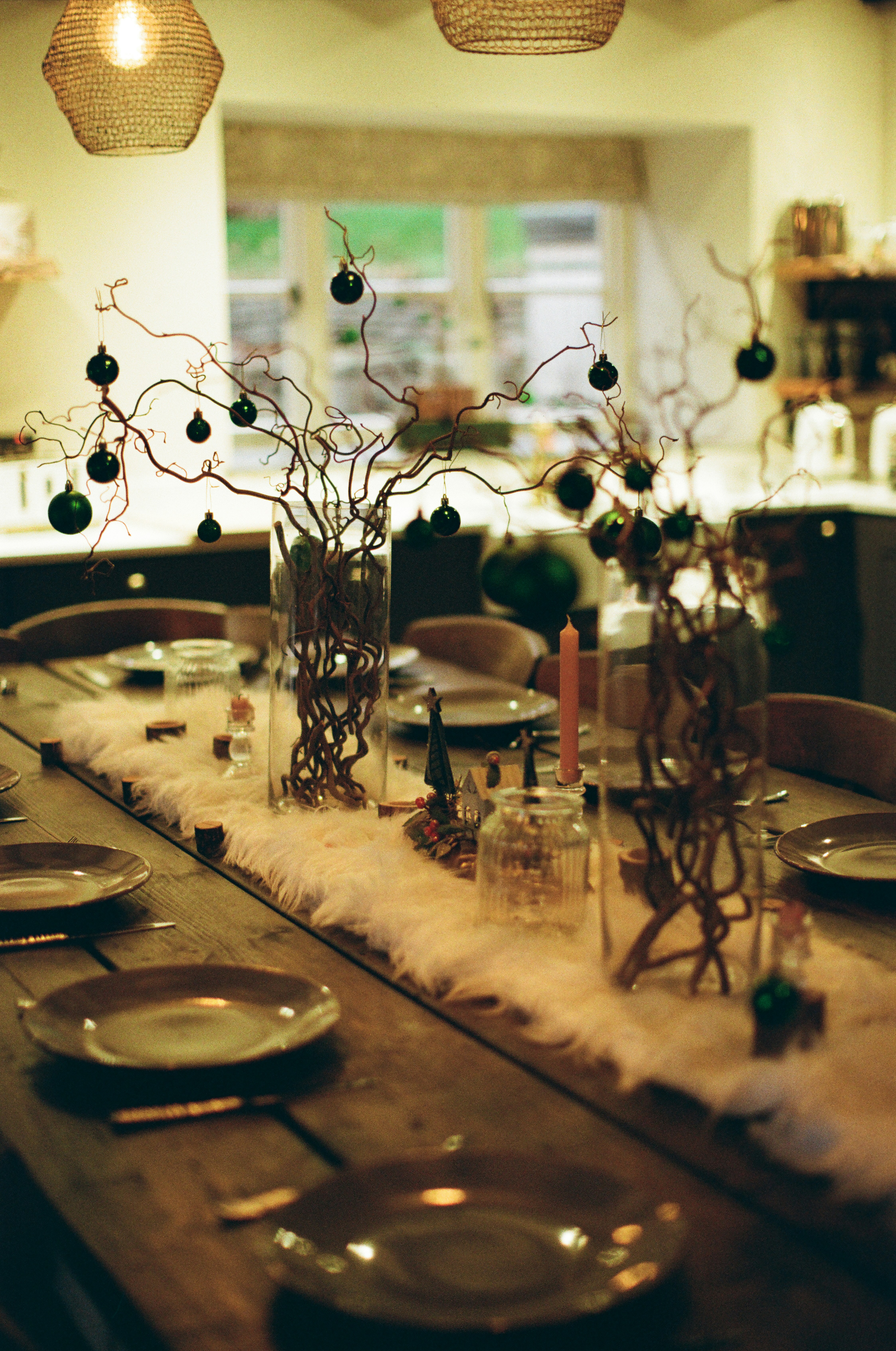 Feestelijk gedekte tafel met vazen, groen en ornamenten.