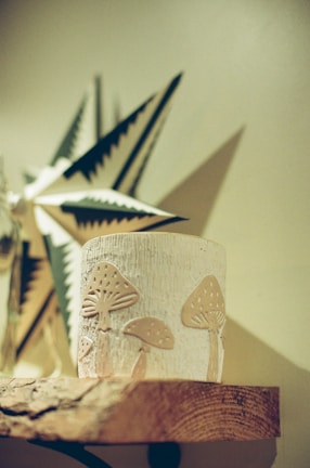 Candle holder with mushroom design on wooden shelf.