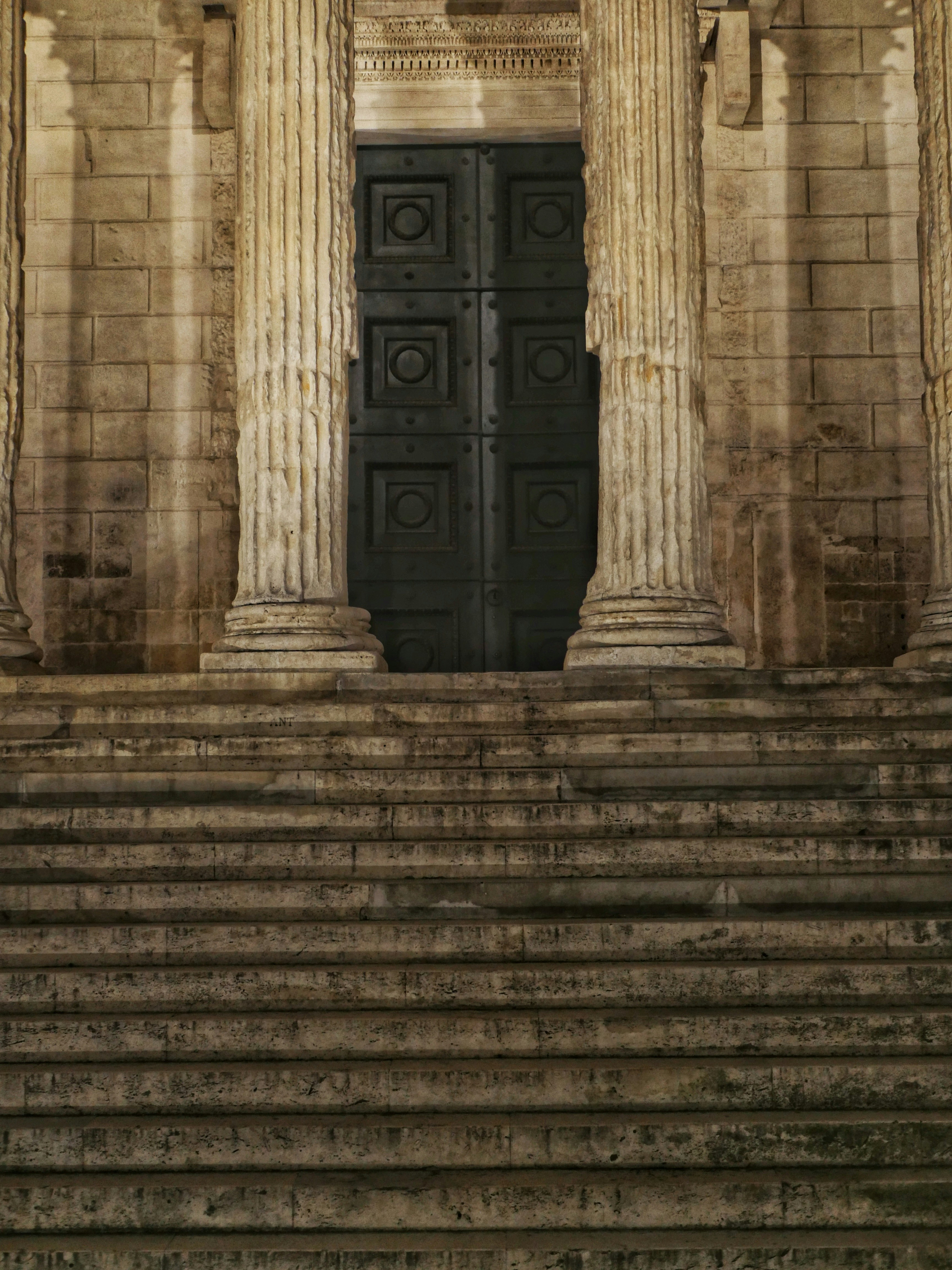 Grande escadaria de pedra que levava a uma grande porta escura.