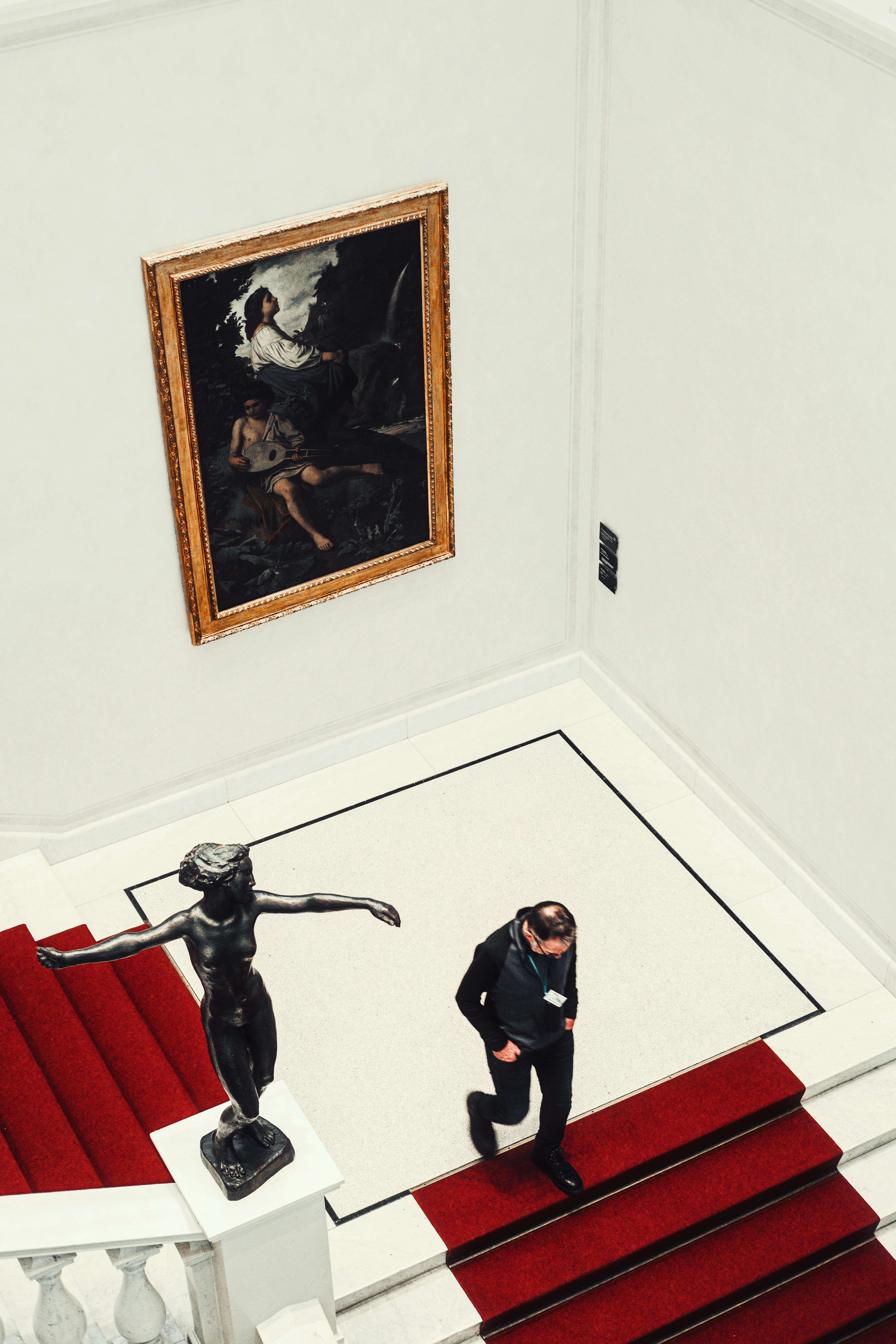 People walk up stairs in a museum near art.