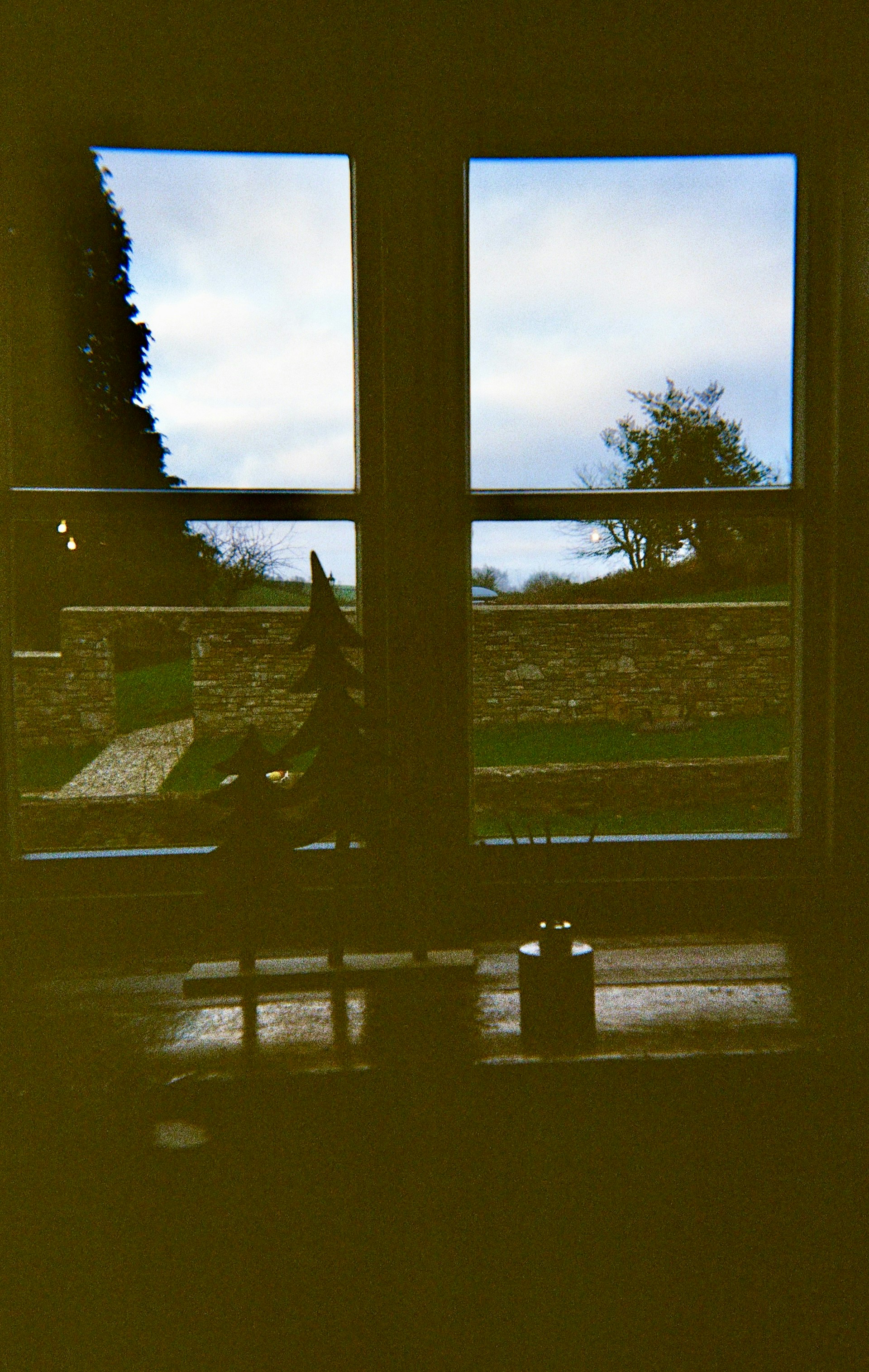 View through a window of a stone wall and trees.
