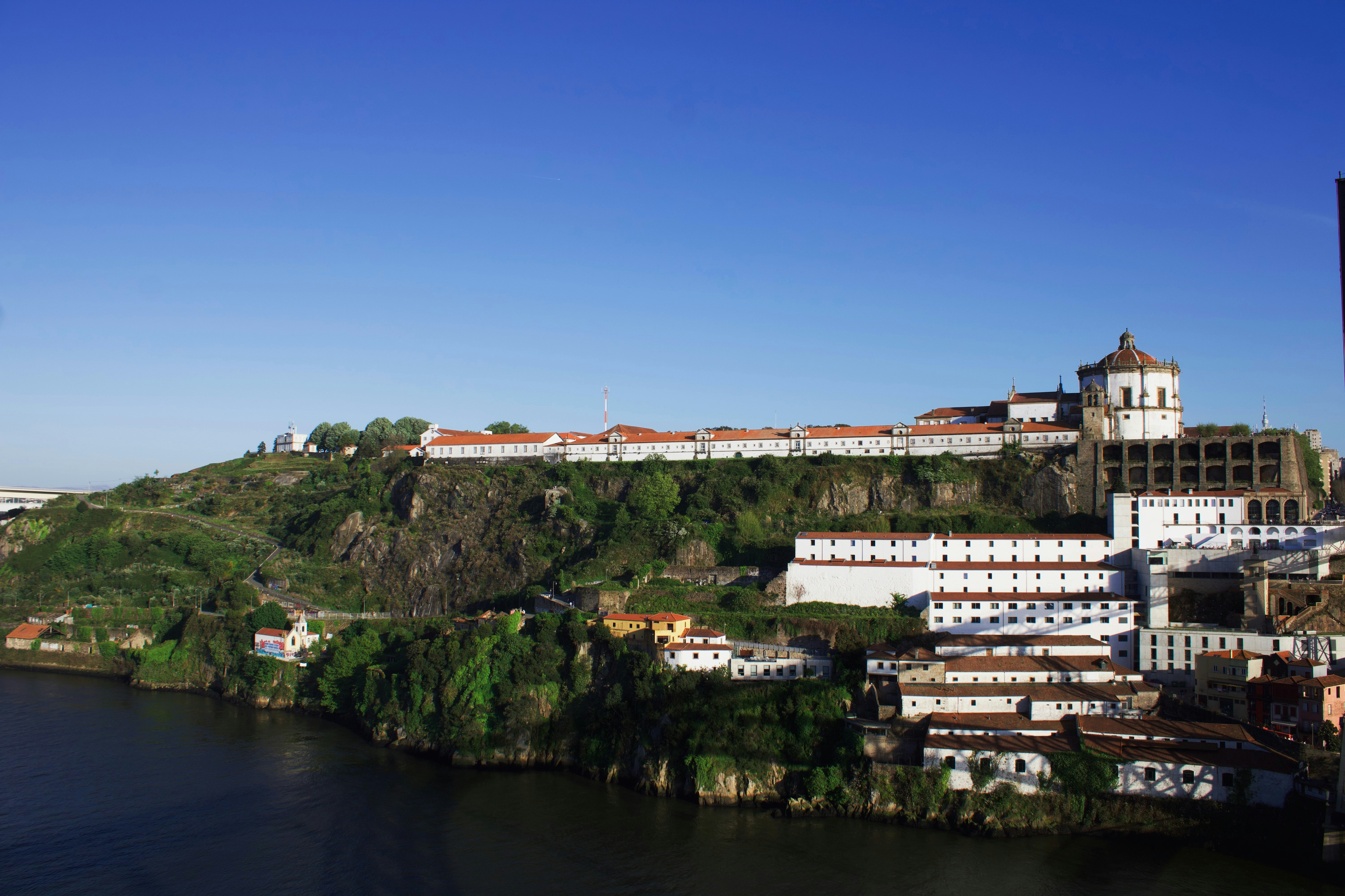 Historic buildings on a green hill overlooking river.