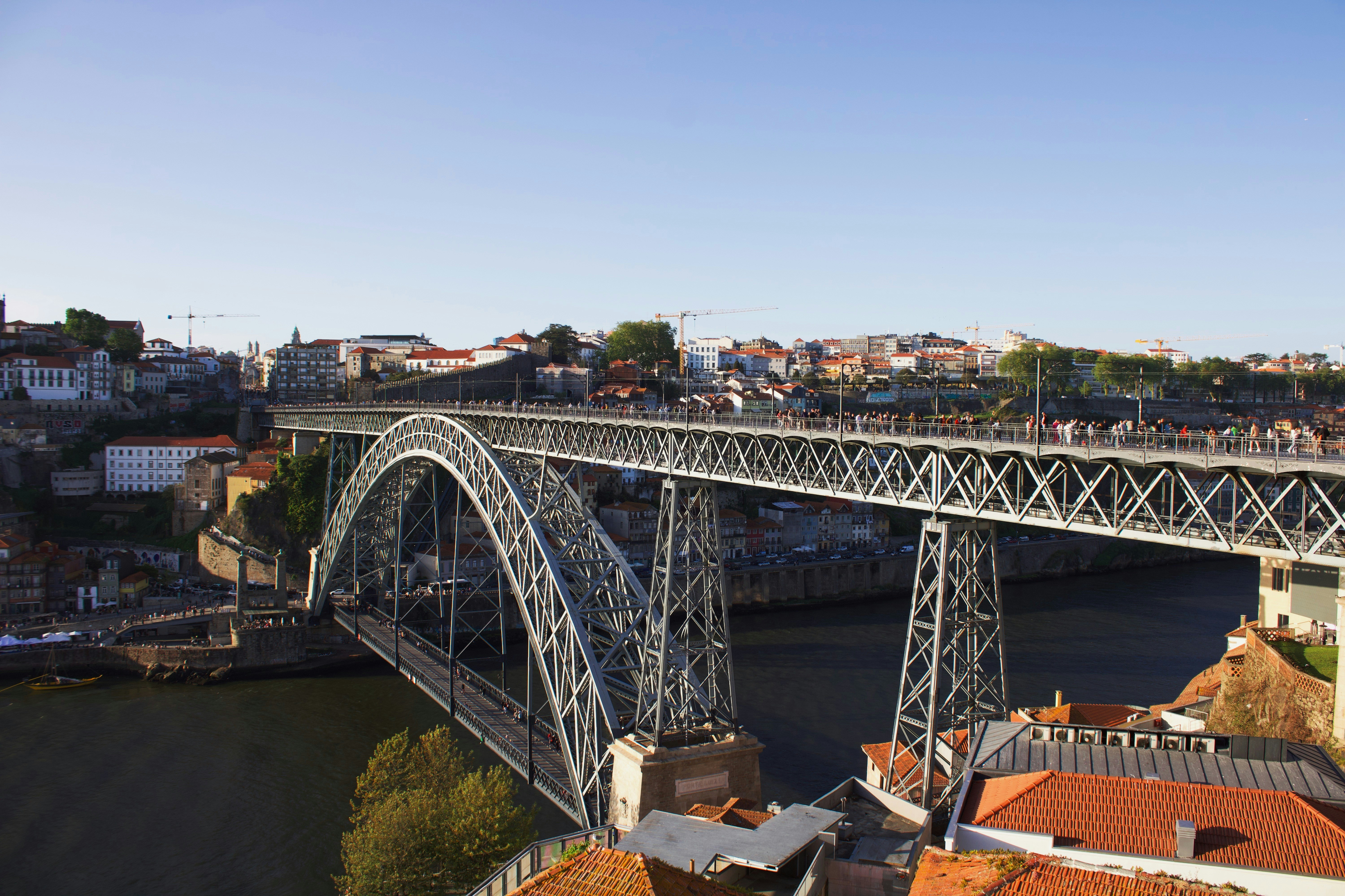 A large metal bridge spans a river in a city.