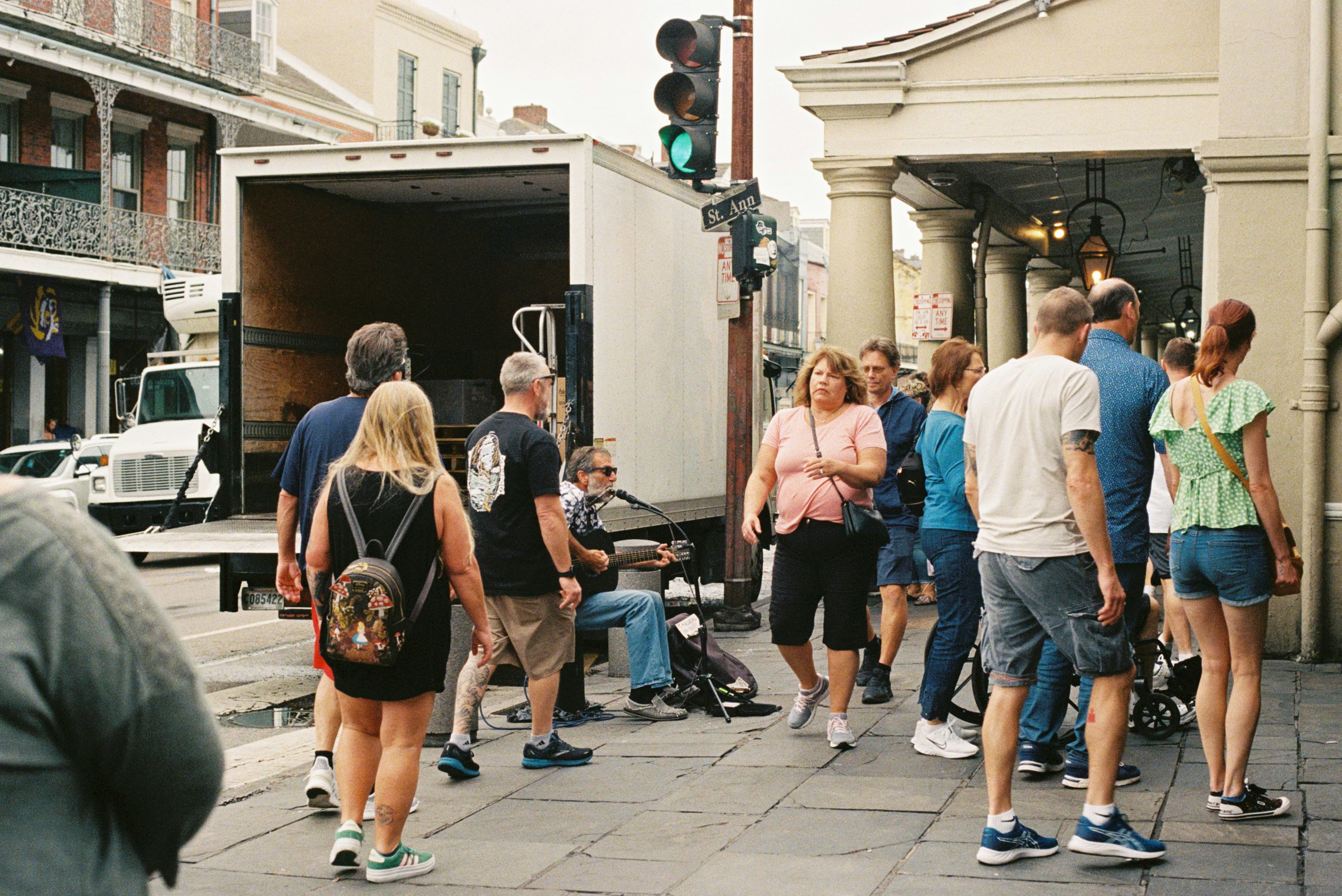 People gathered on a sidewalk near a moving truck.