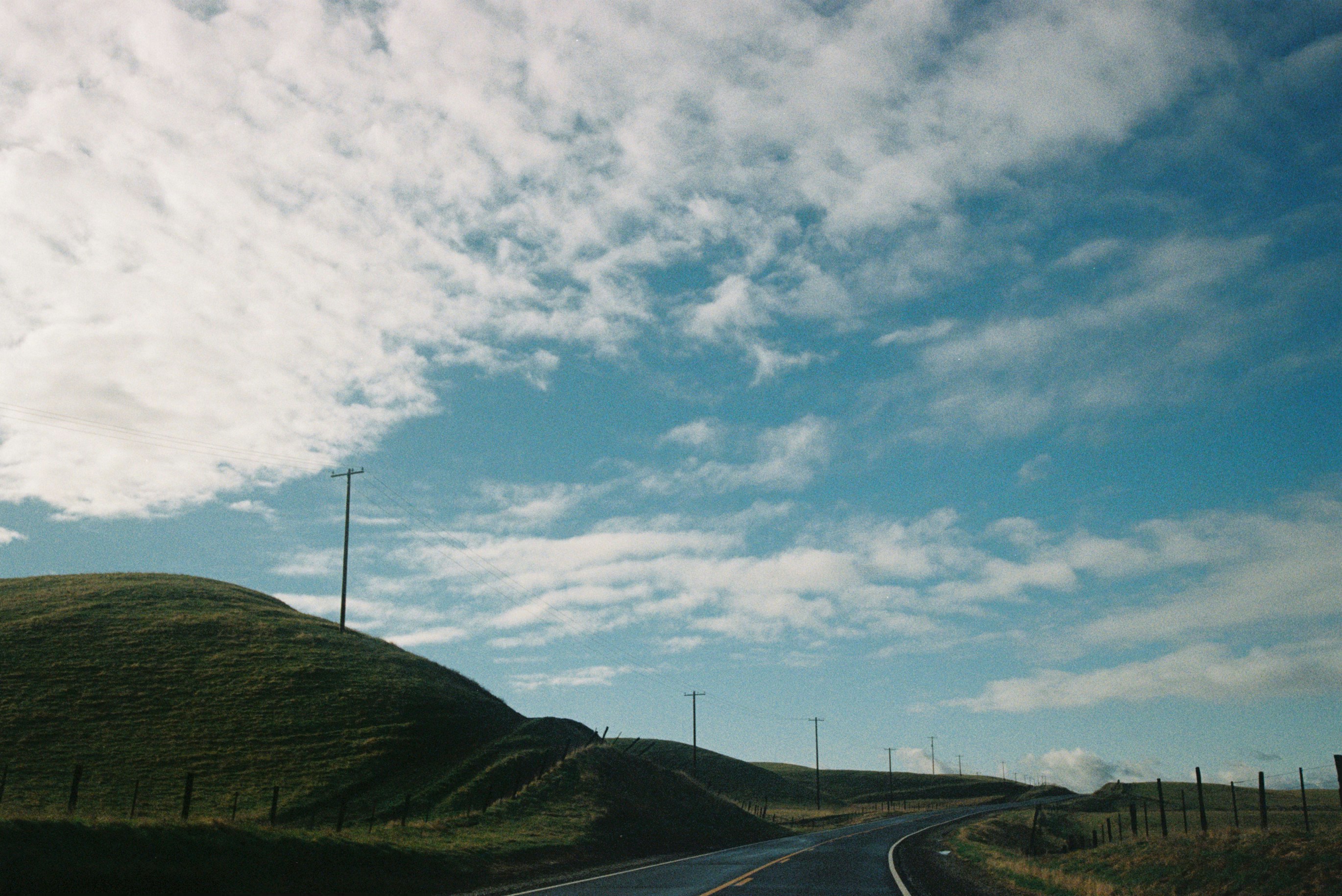 A winding road through green hills under a cloudy sky