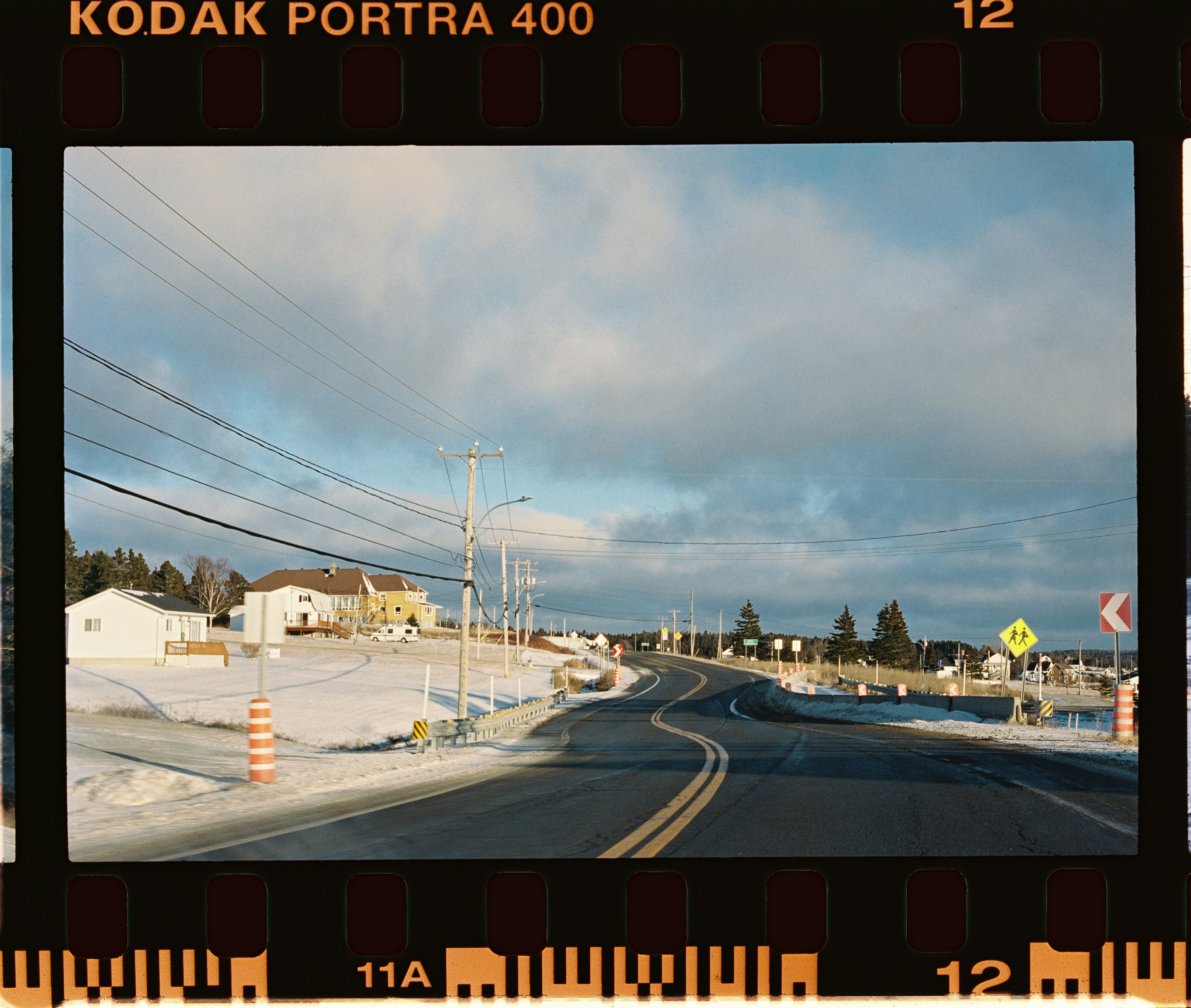 Winding road through a snowy landscape under cloudy sky