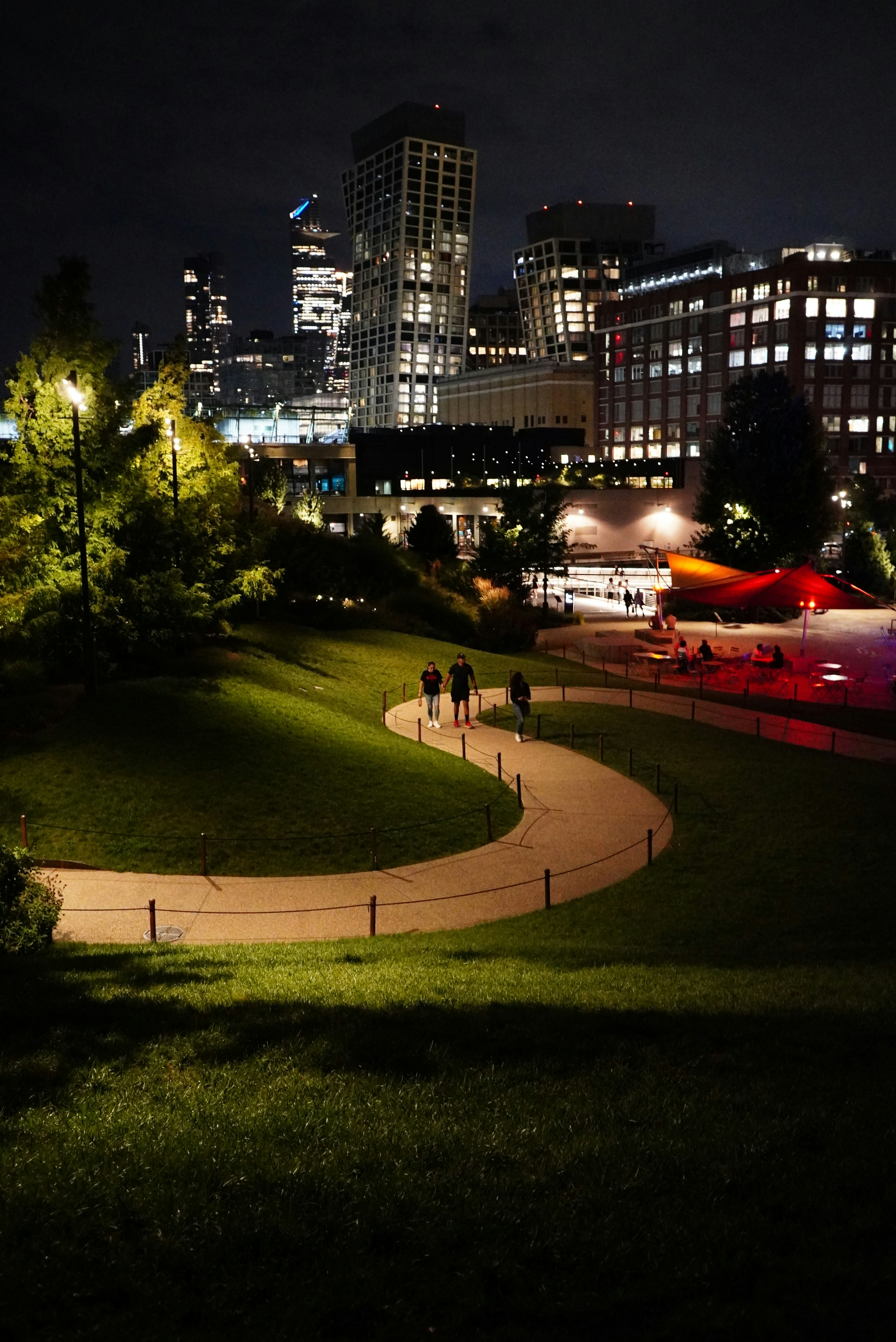 People walk on a path in a park at night.