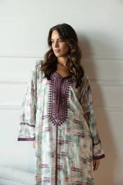 Woman wearing a patterned kaftan with embroidered neckline.
