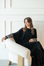 Woman in elegant black dress sitting in chair