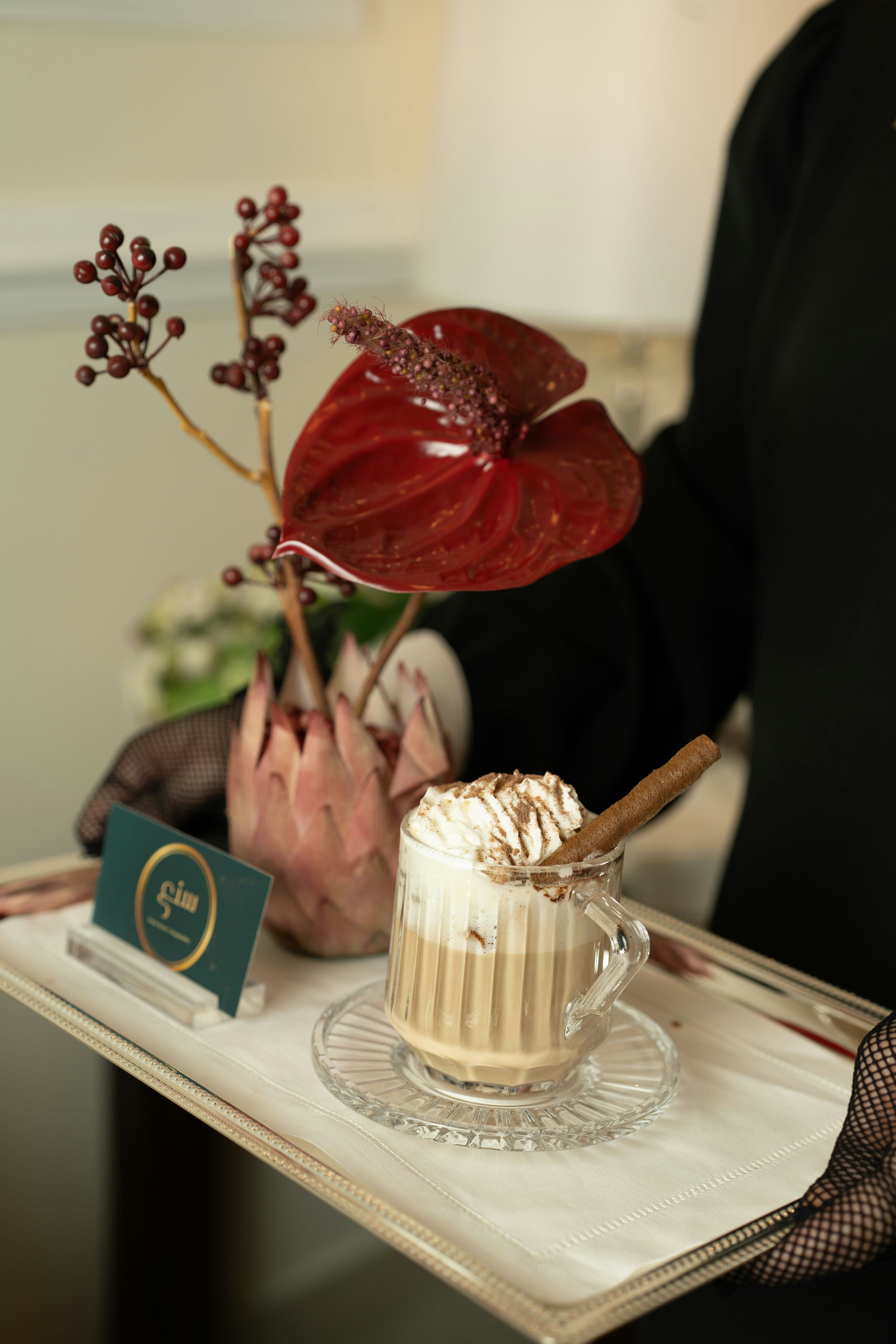 Ein Latte mit Schlagsahne und Zimt auf einem Tablett.