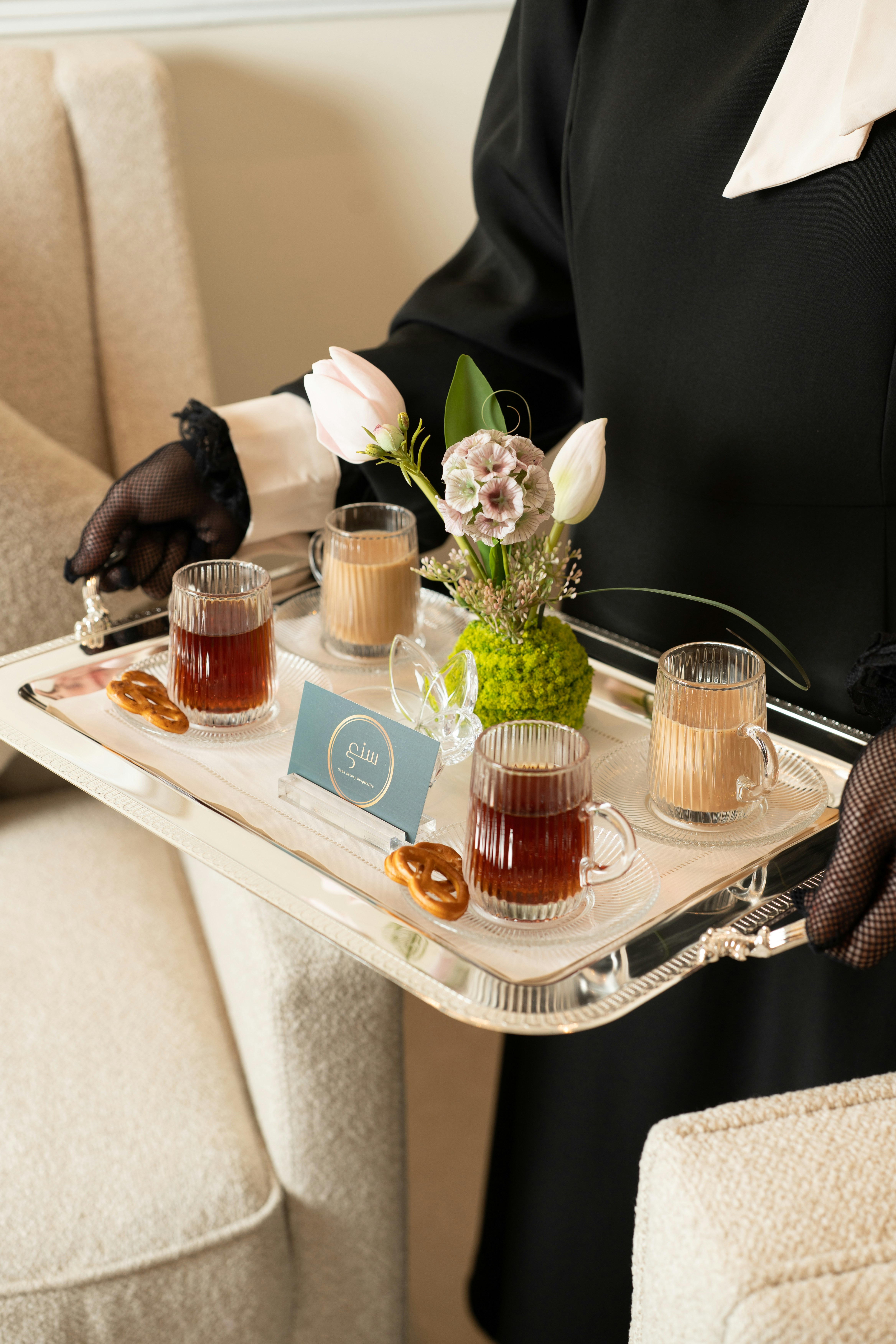 Person, die Getränke und Snacks auf einem silbernen Tablett serviert